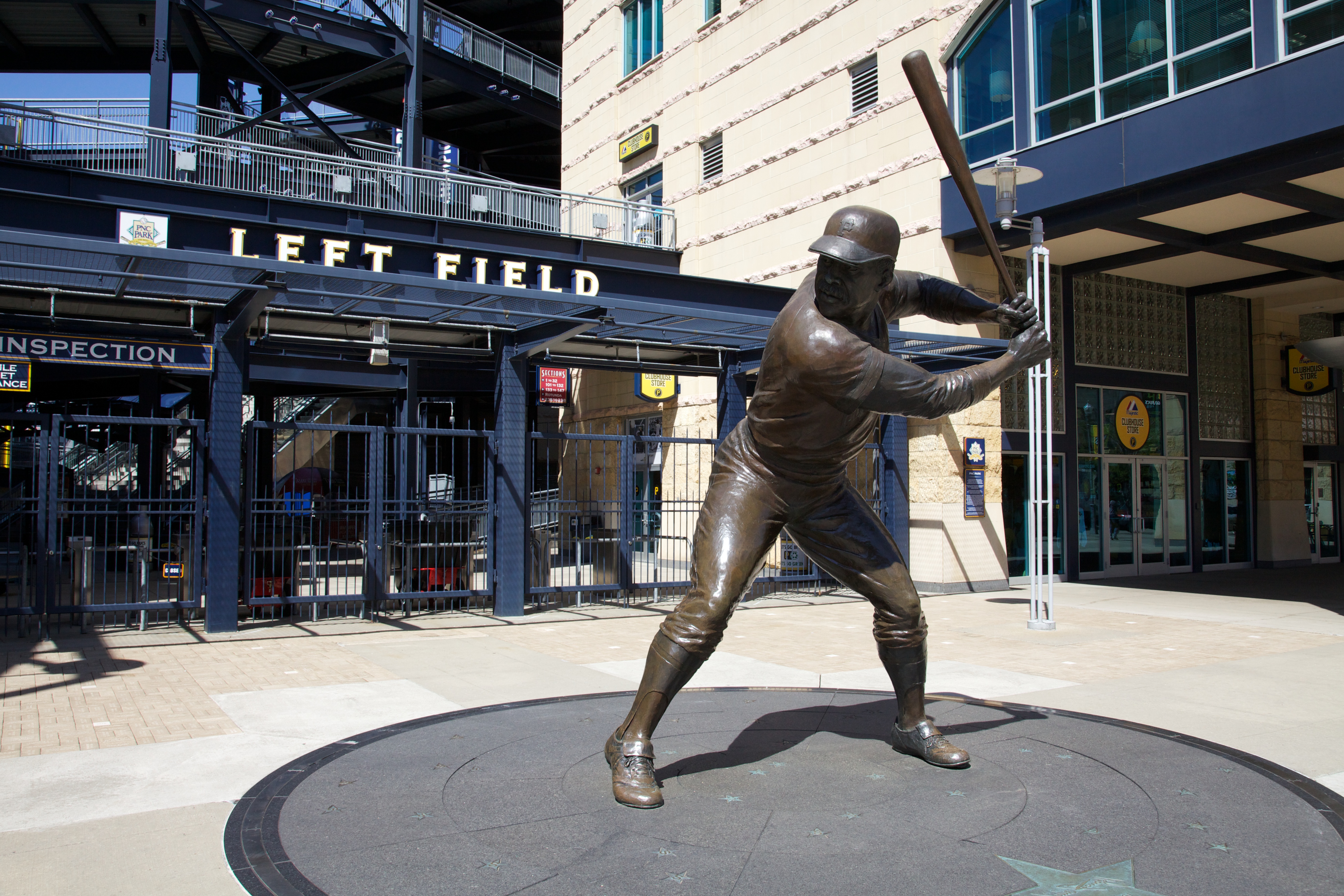 Bronze statue of a baseball player in batting stance outside a stadium entrance.