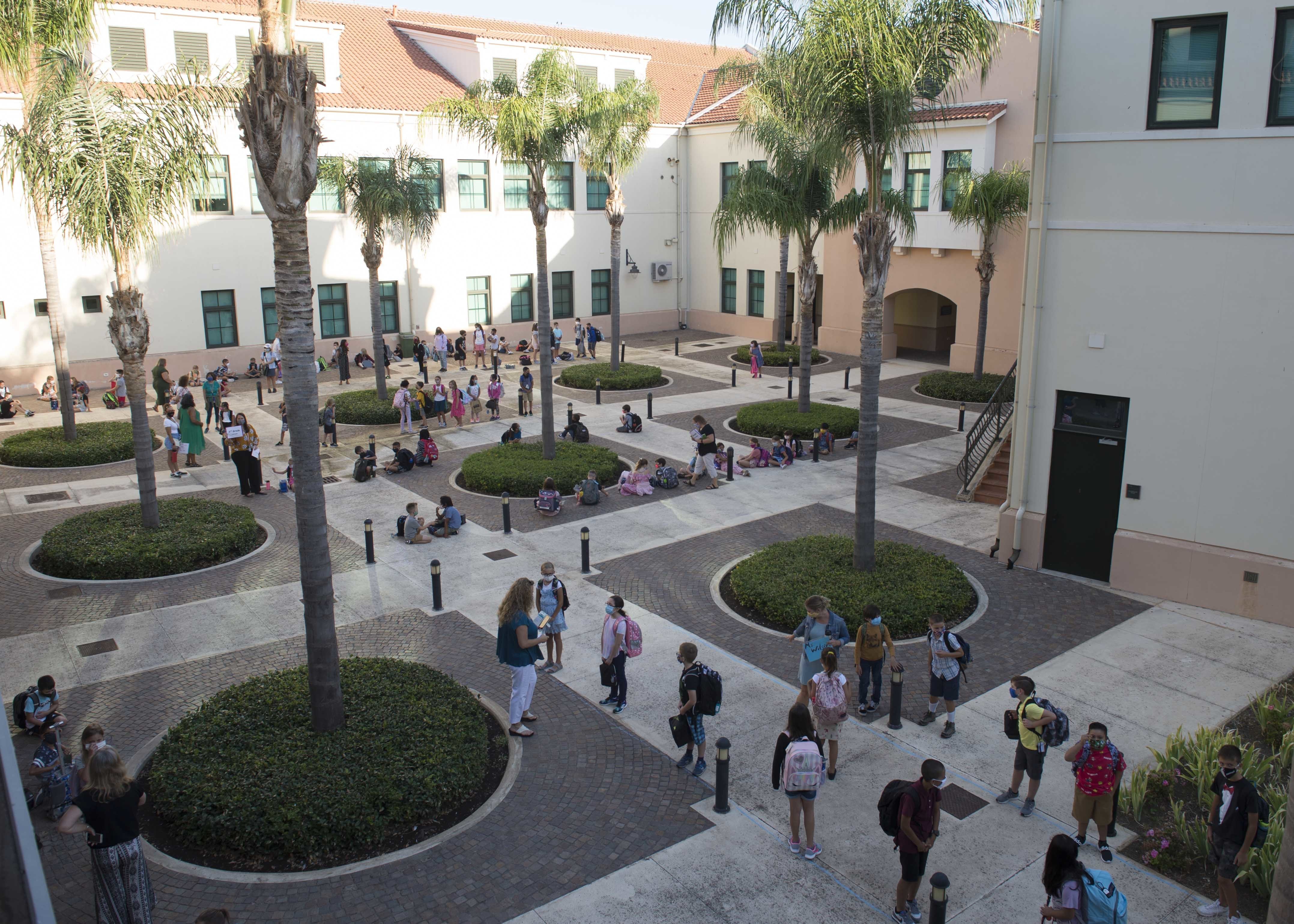 Students wearing backpacks gathered in a school courtyard on the first day of school.