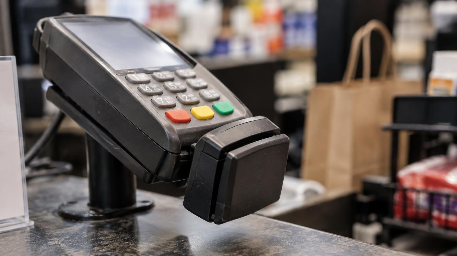A card skimming device attached to a payment terminal on a checkout counter.