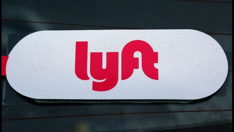 A white oval Lyft logo sign with red lettering affixed to a car window.