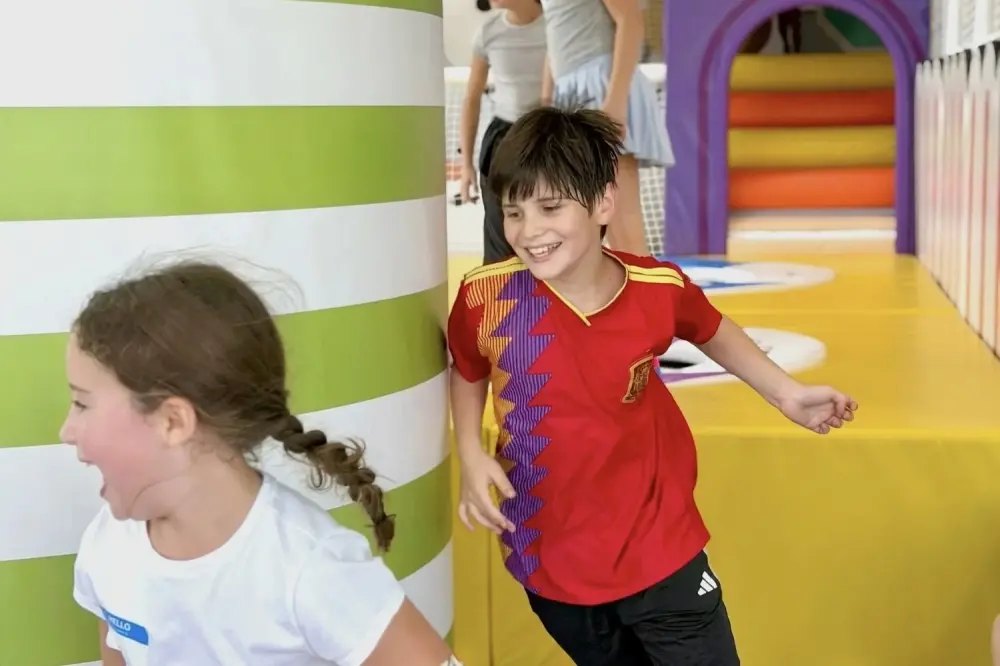 Two children running and laughing inside a brightly colored indoor play facility.