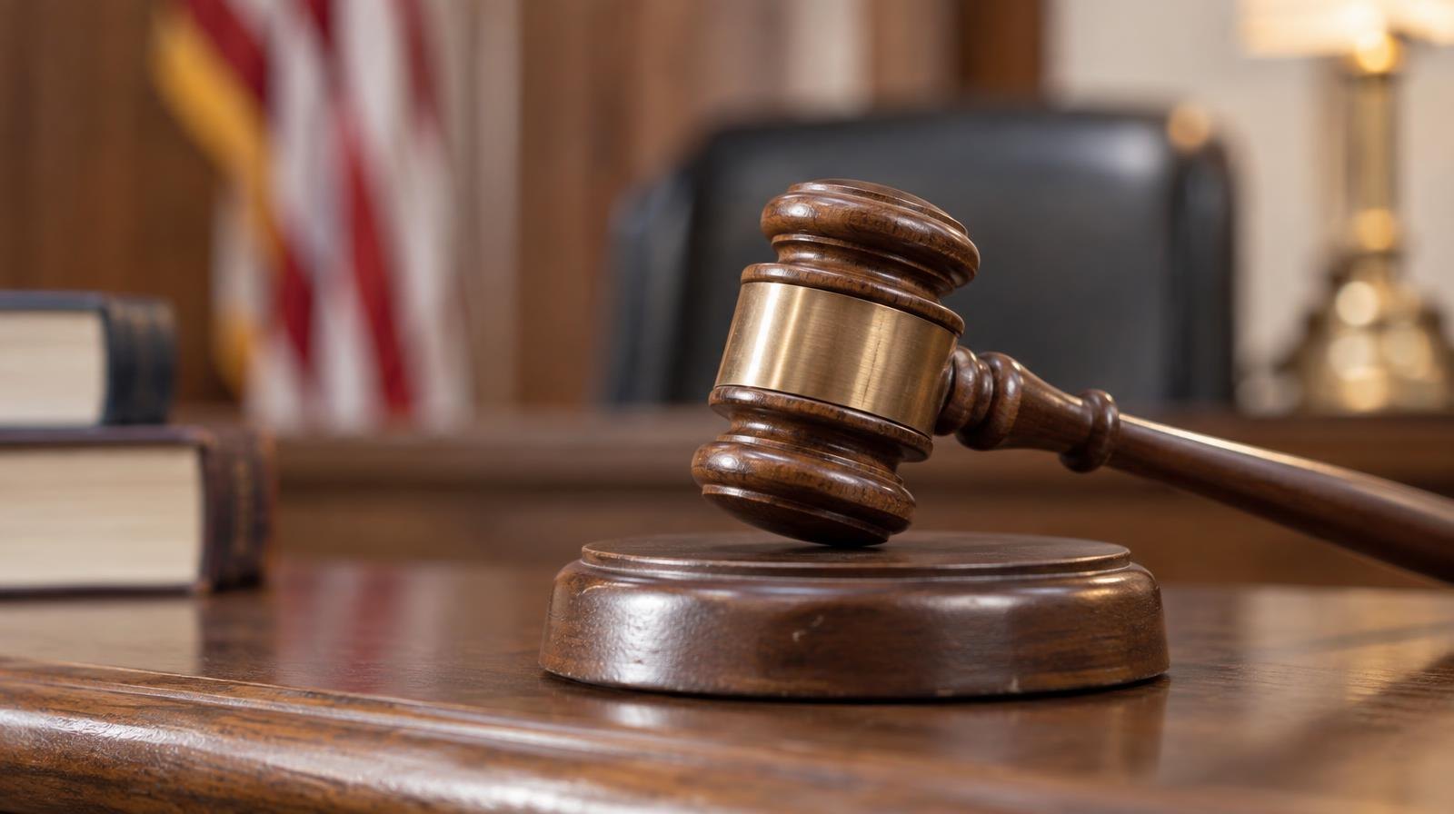Wooden gavel resting on its sound block on a courtroom bench.