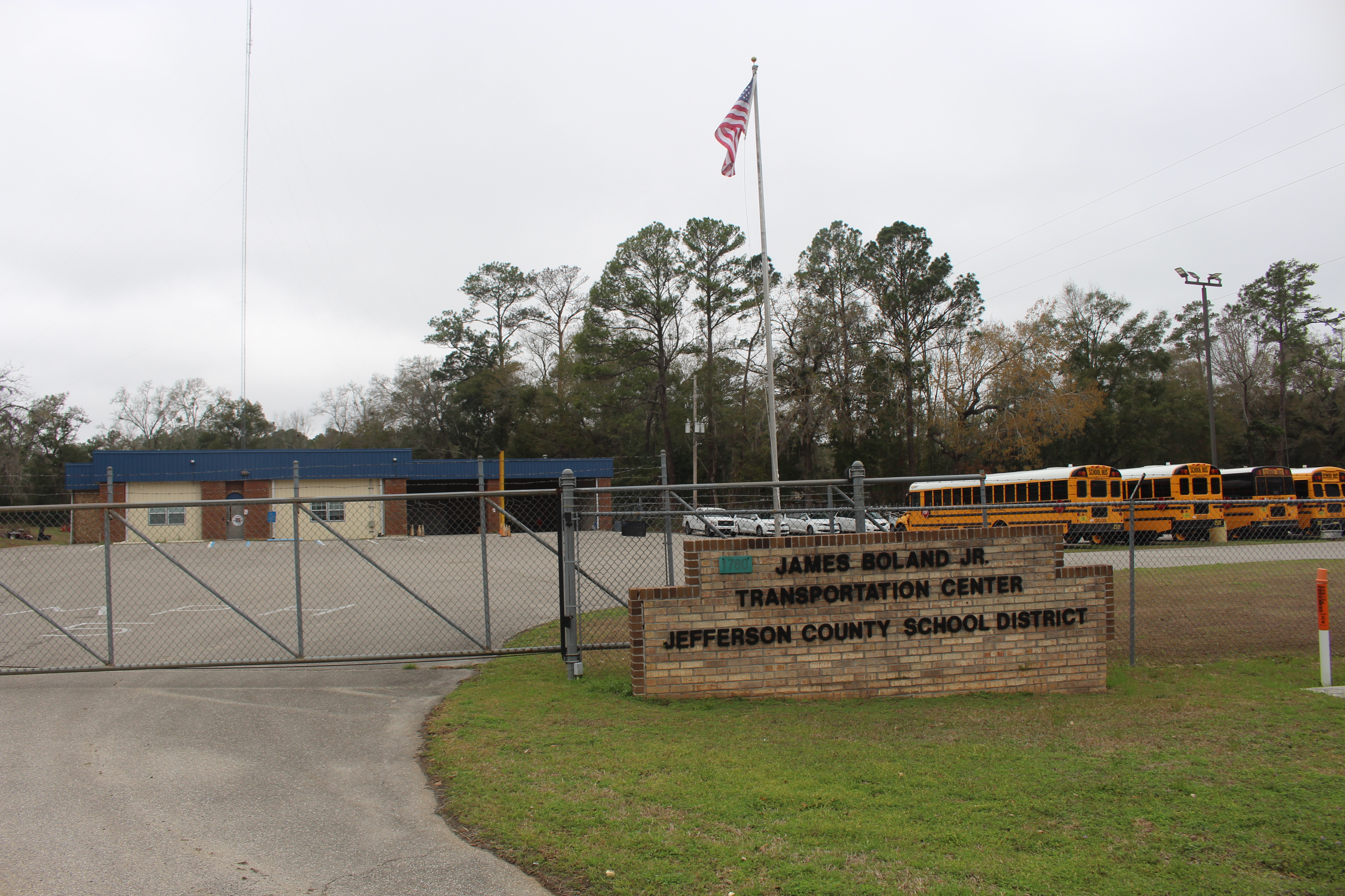 Rows of yellow school buses parked behind a chain-link fence at a transportation center.