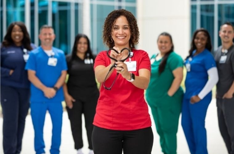 Healthcare workers in colorful scrubs pose together in a bright modern facility.