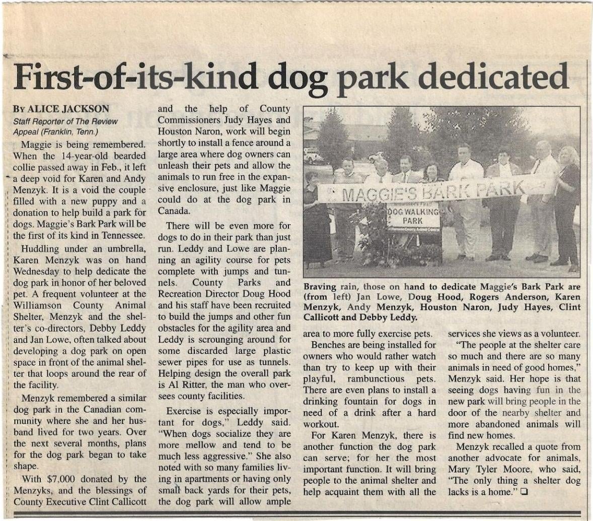Scanned newspaper article with headline about a dog park dedication and a group photo of attendees.