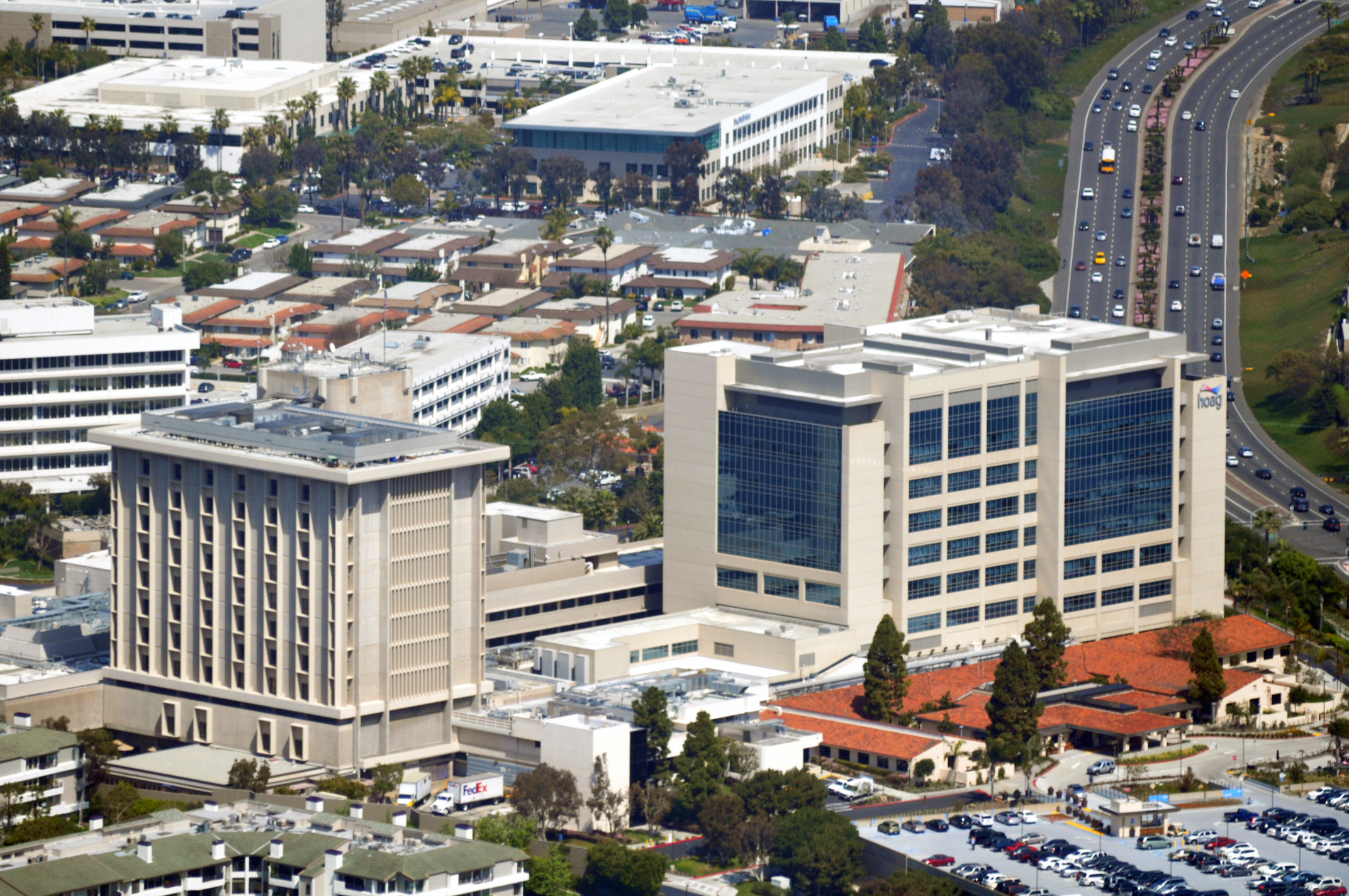 Aerial view of a multi-building hospital campus alongside a busy multi-lane highway.