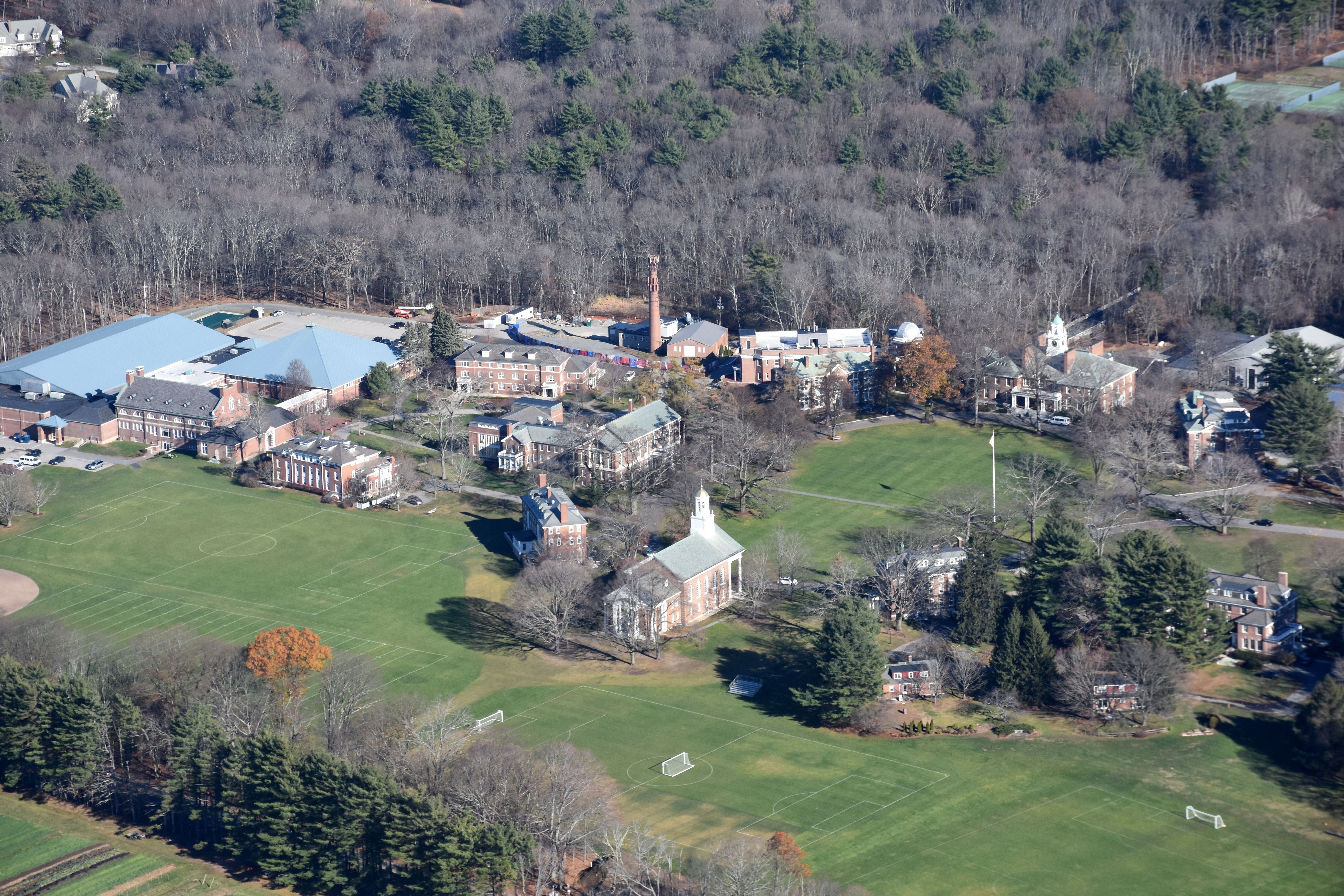 Aerial view of a boarding school campus with brick buildings, athletic fields, and autumn trees.