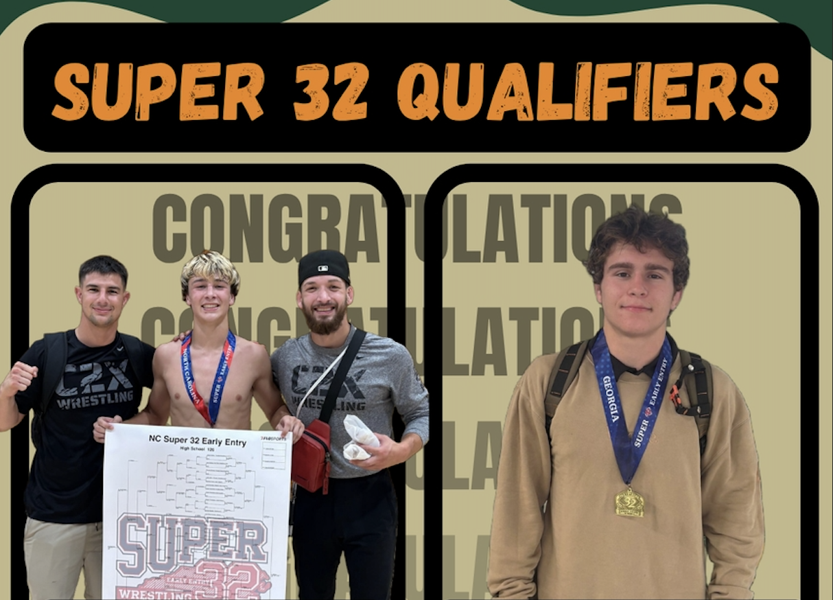 Two wrestlers wearing gold medals pose with a coach holding a tournament bracket sheet.