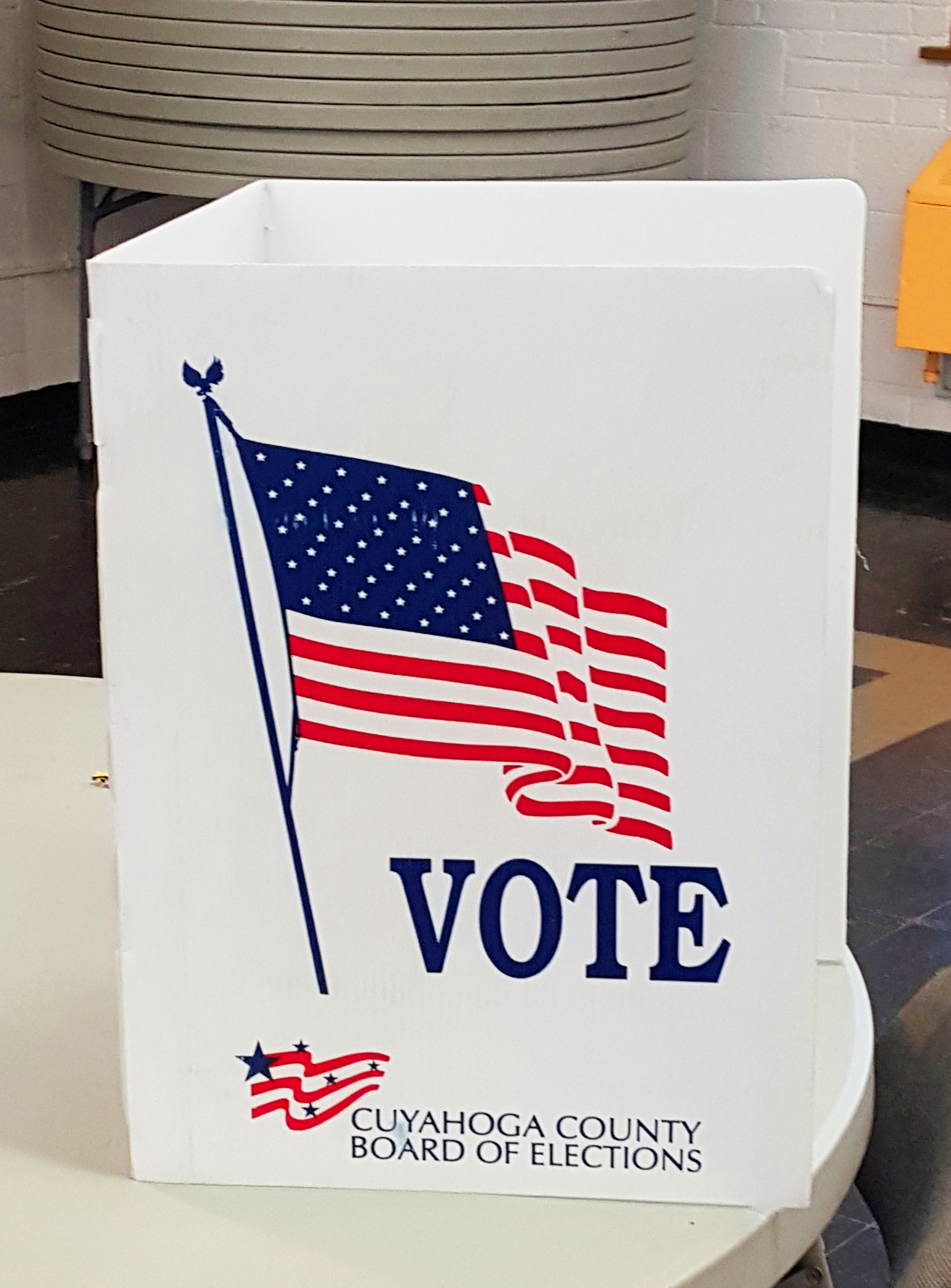 White voting booth on a table with an American flag graphic and the word VOTE.