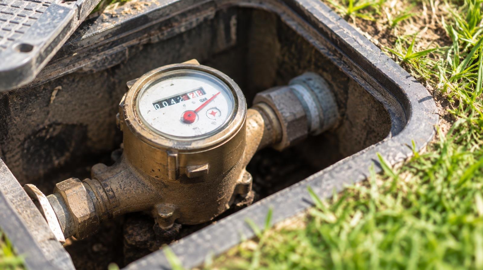 Close-up of a brass-dial water meter in an outdoor utility box.