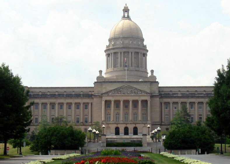 Kentucky State Capitol building with large dome, columns, and flower beds in foreground.