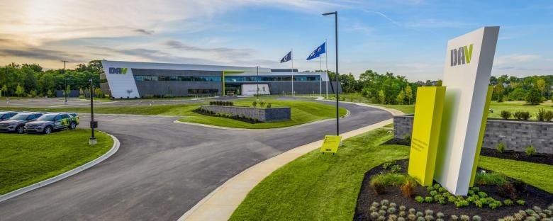 Modern corporate headquarters building with DAV logo on facade and flags out front.