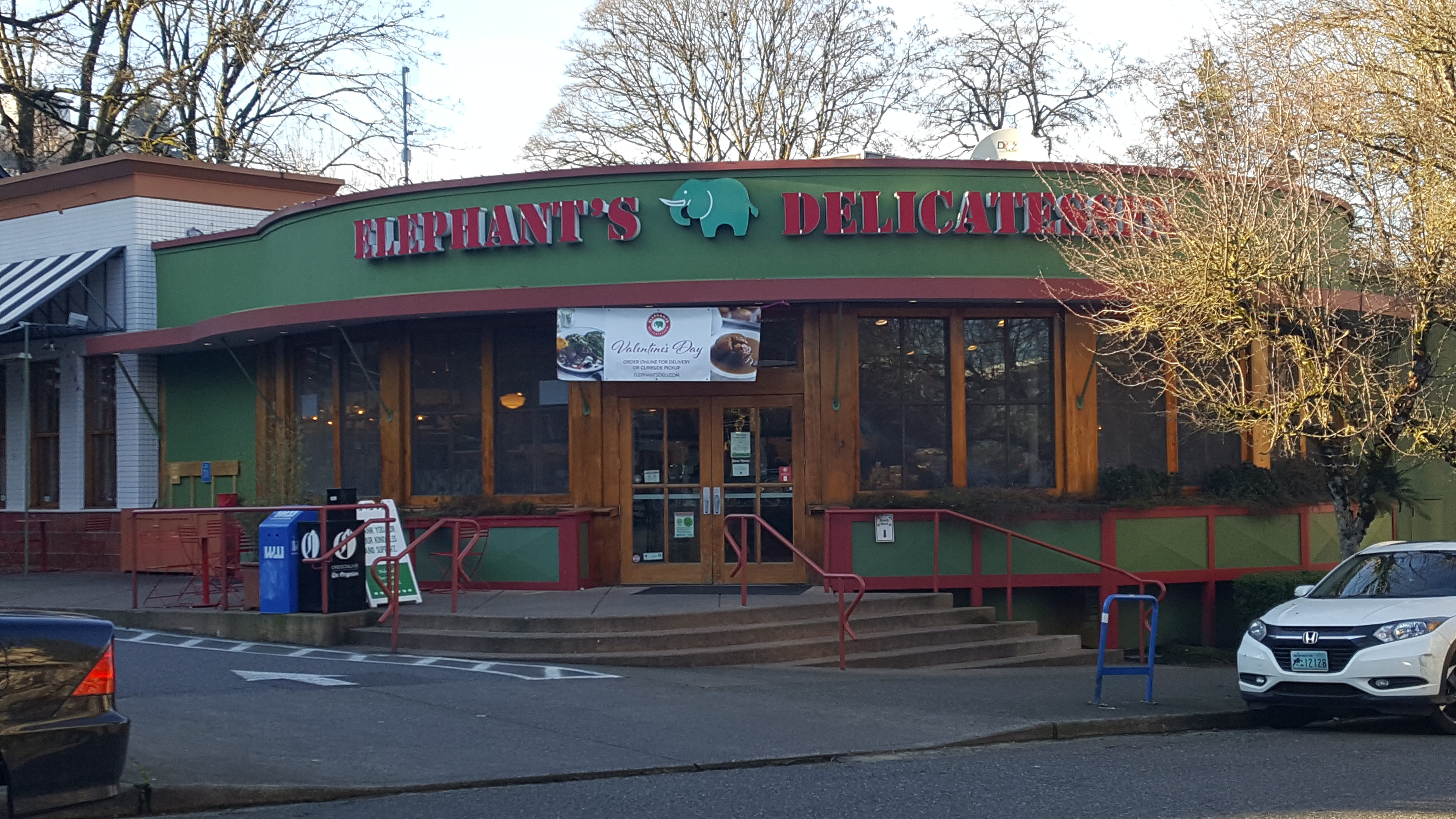 Single-story green-trimmed building with Elephants Delicatessen signage and an accessible entrance ramp.
