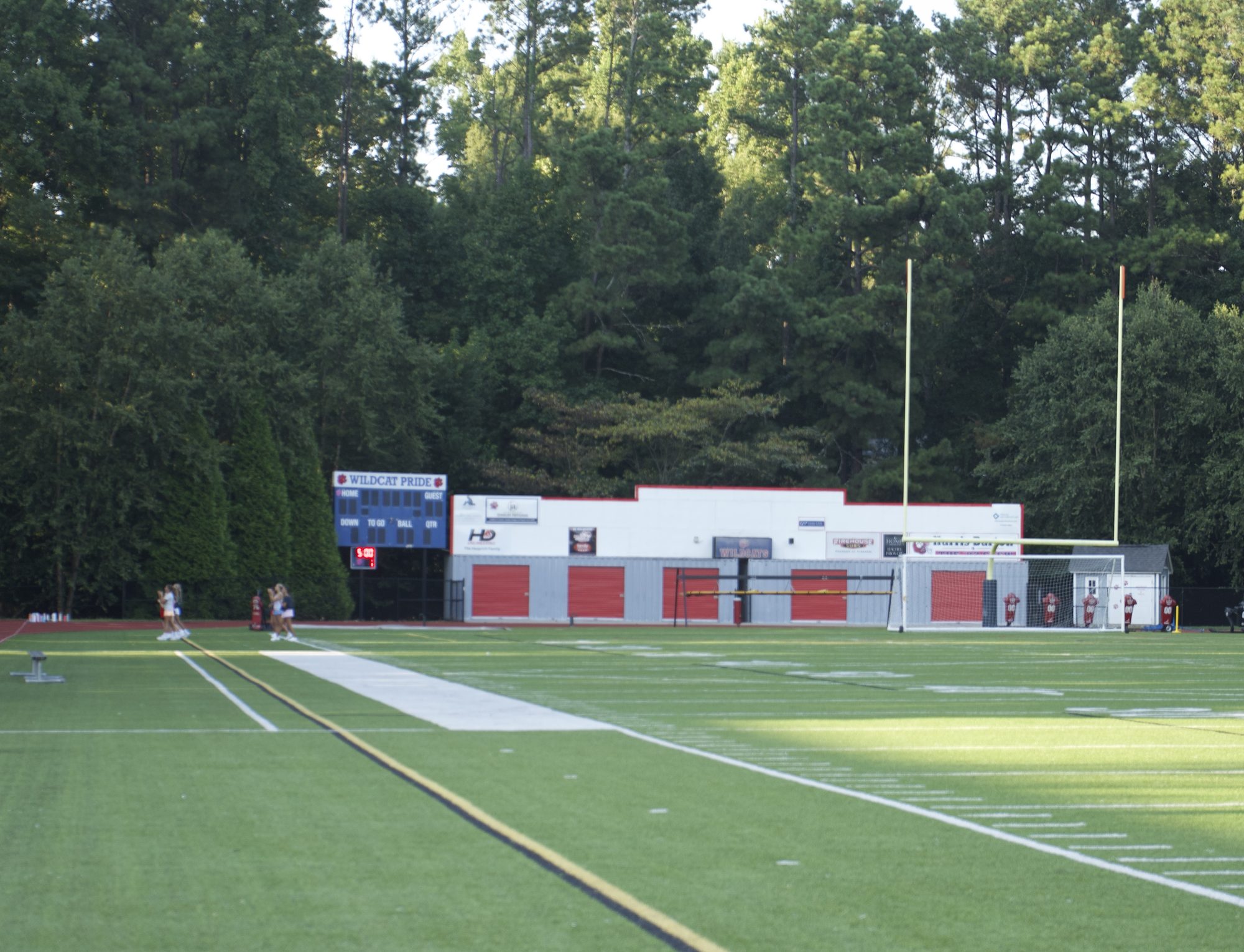 Artificial turf sports field at dusk with scoreboard reading Wildcat Pride