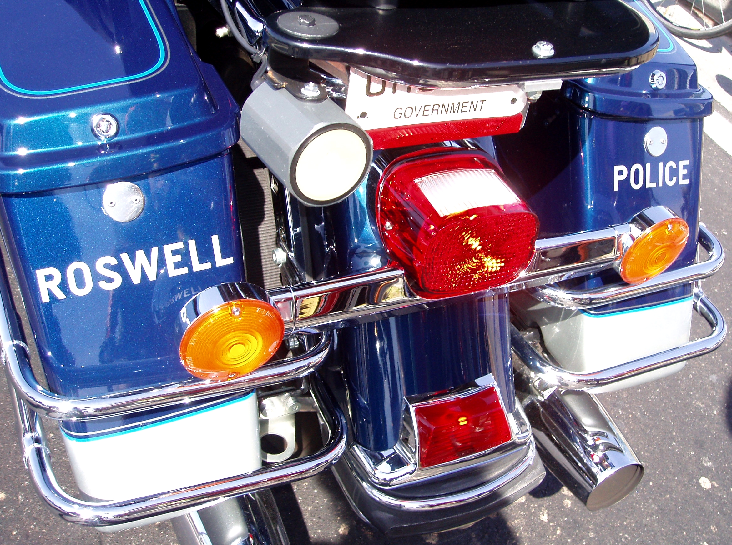 Rear view of a Roswell Police motorcycle with blue saddlebags labeled ROSWELL and POLICE.