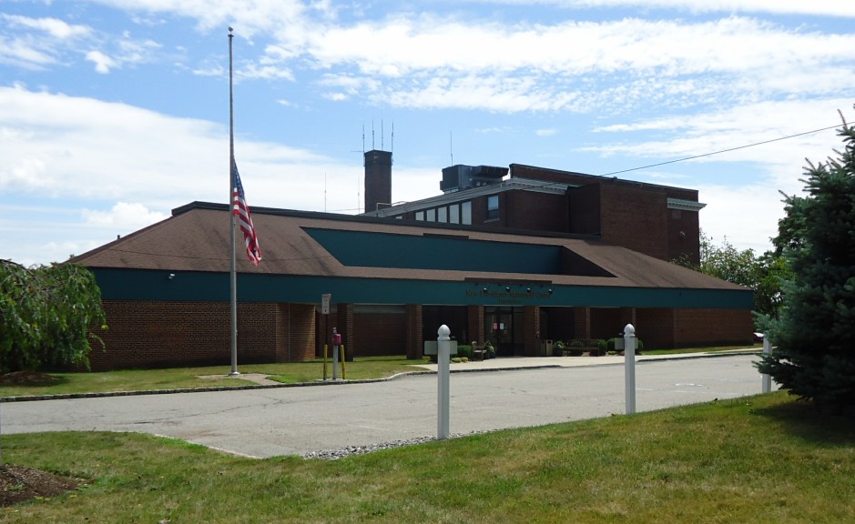 Brick municipal building with an American flag on a flagpole out front.