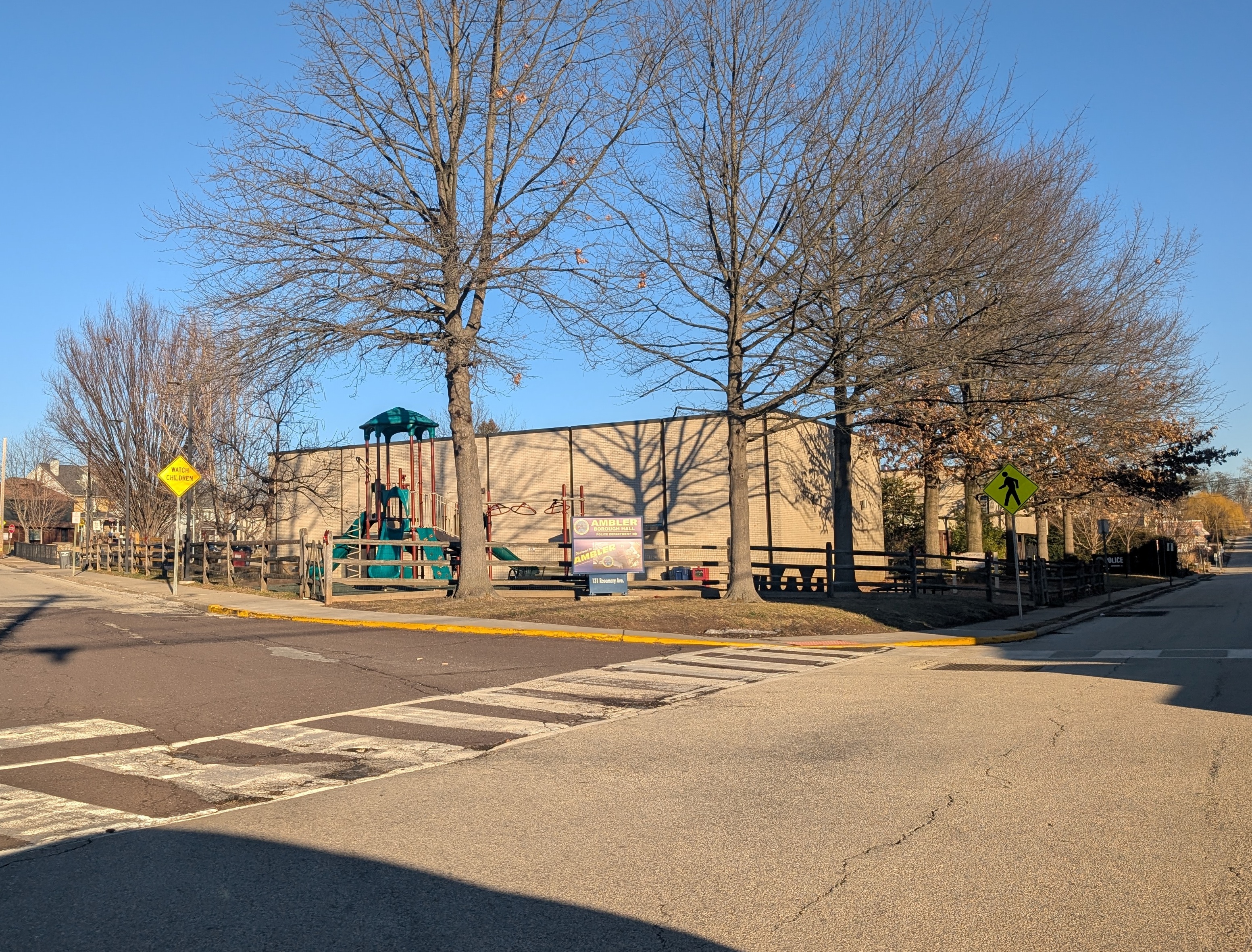 Stone municipal building at a street corner with bare trees in winter.