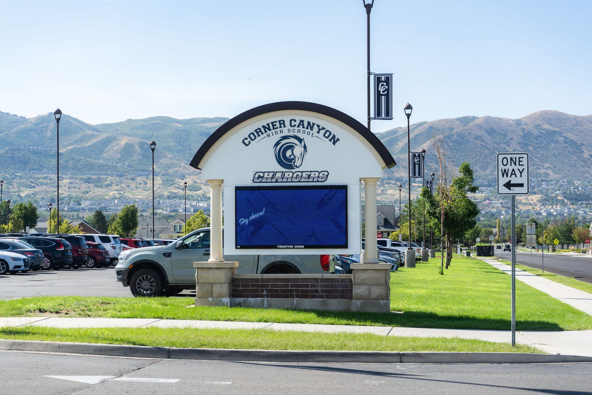 Monument entrance sign for a high school with mascot logo and LED display board