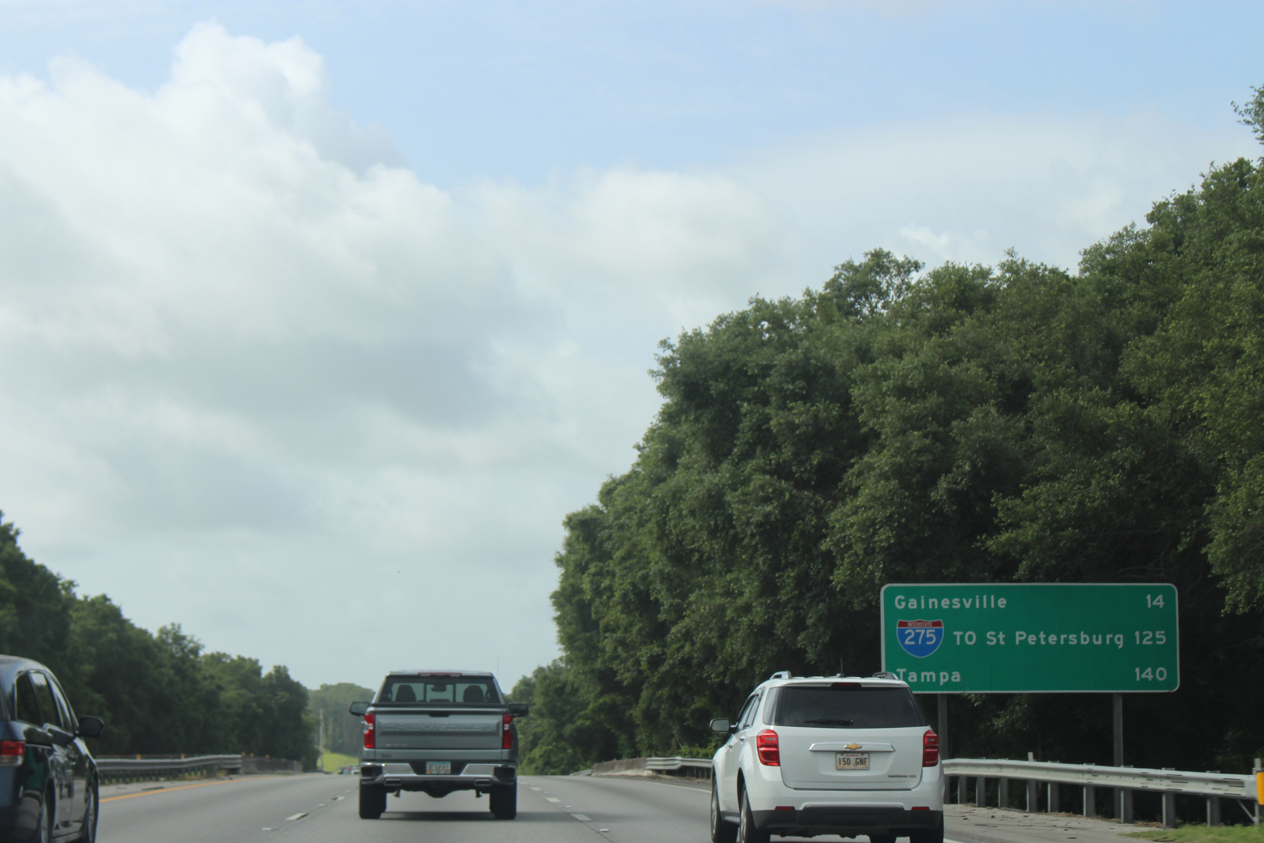 Green overhead highway sign showing distances to I-275, Tampa, and Gainesville.