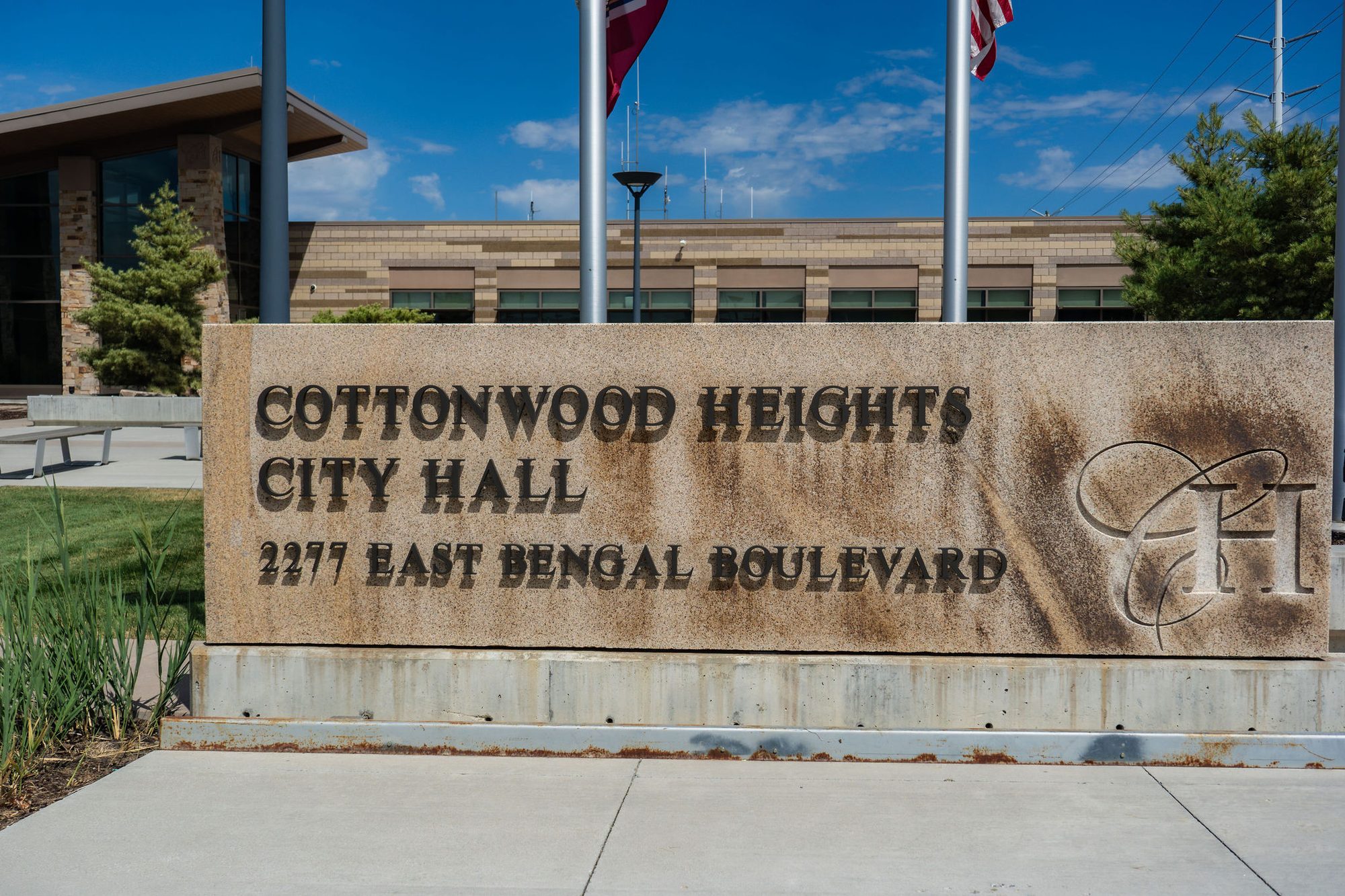 Stone entrance sign for Cottonwood Heights City Hall in front of a modern brick building with flagpoles.