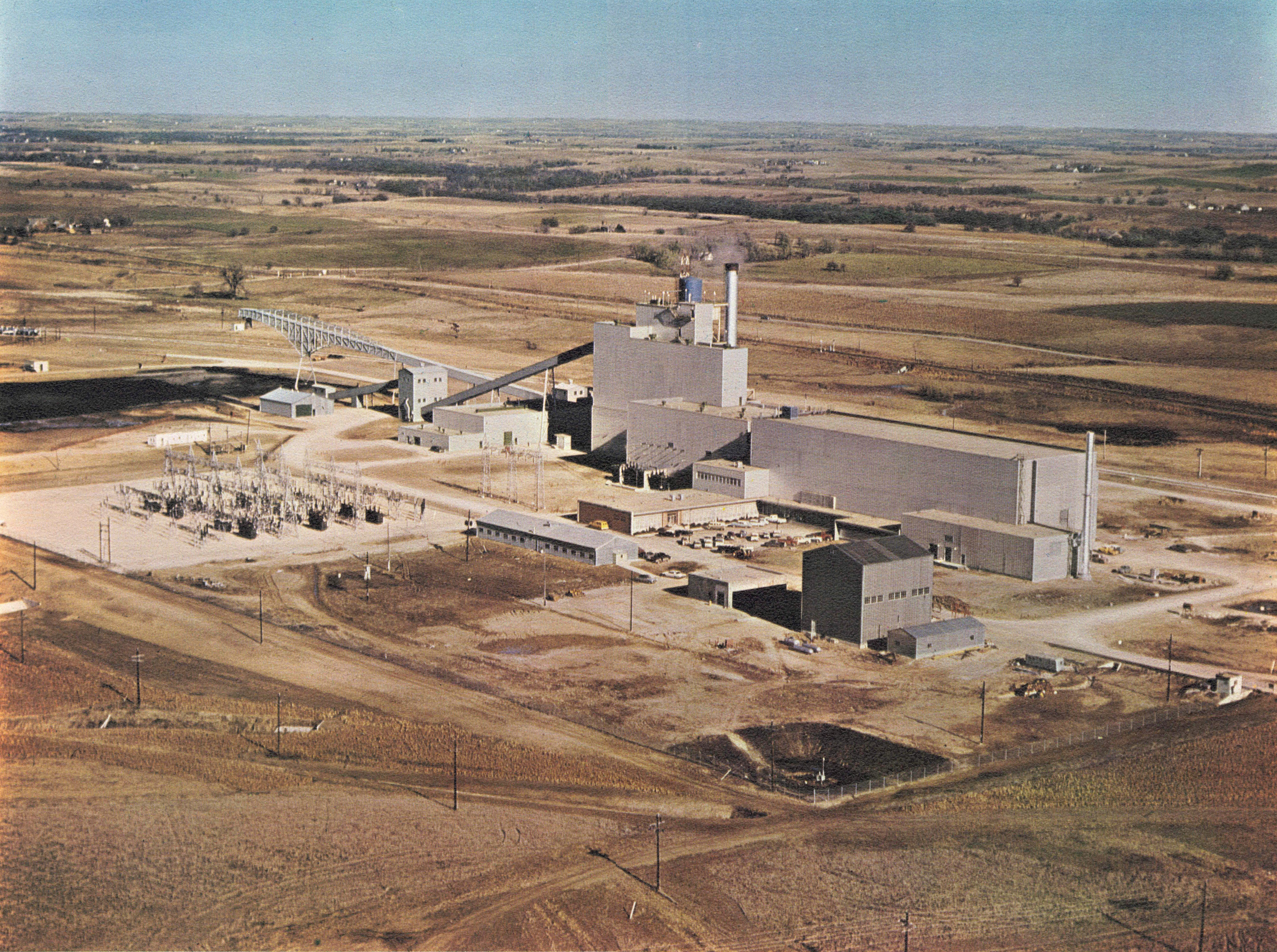 Aerial view of a nuclear power station and adjacent industrial plant on flat farmland.