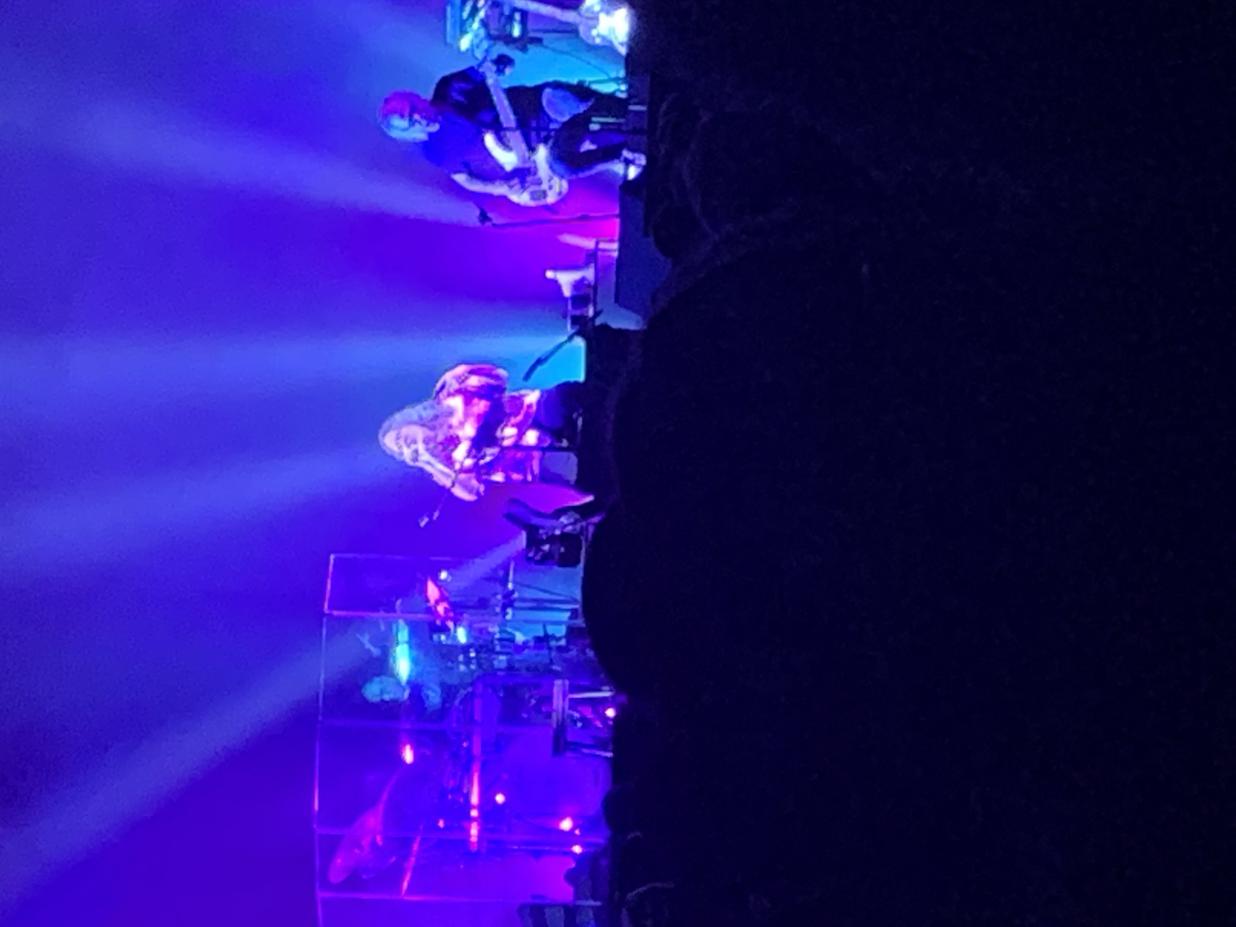 Band performing on a dimly lit stage under blue and purple spotlights.