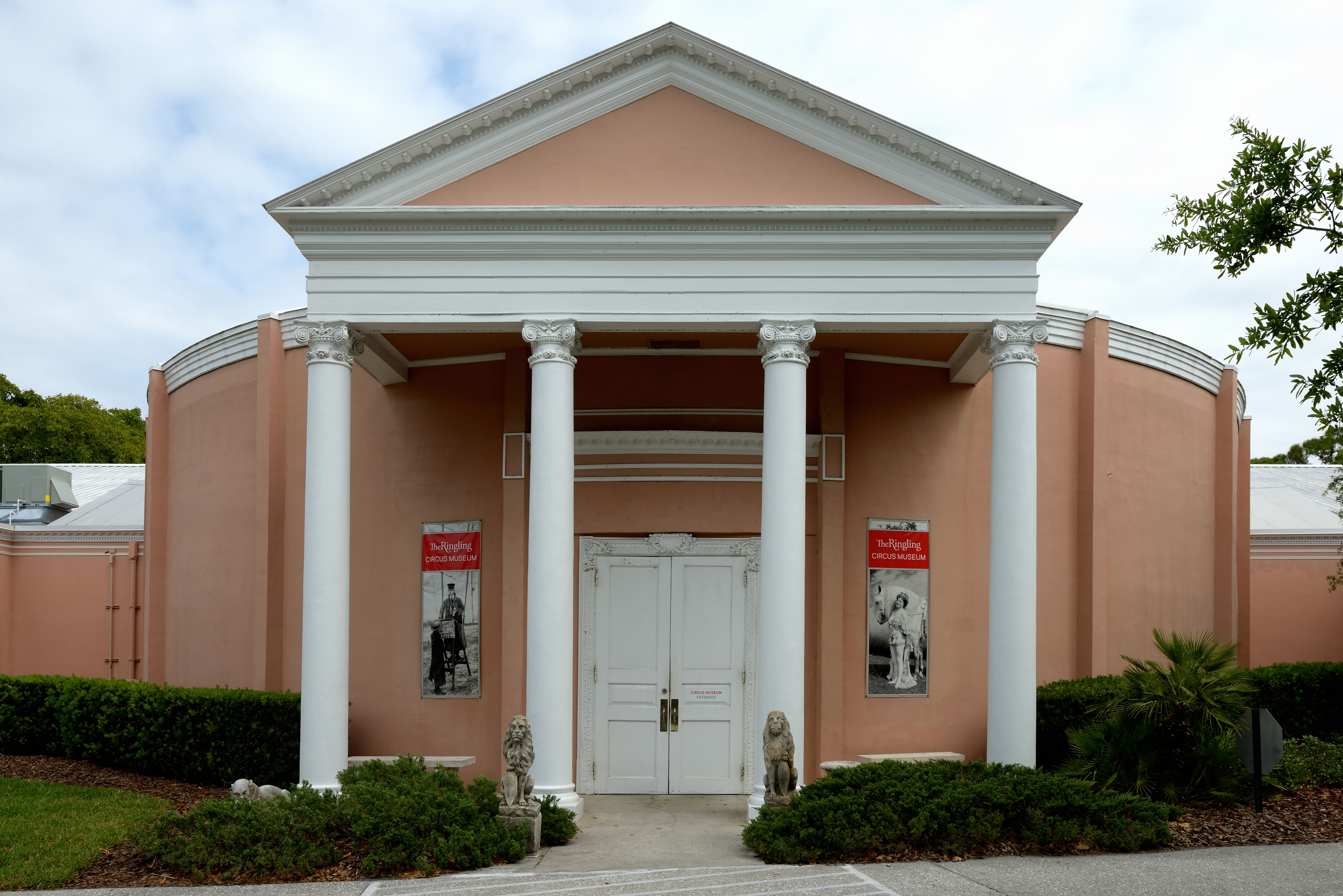 Pink neoclassical building with white columns and entrance banners on a museum campus.