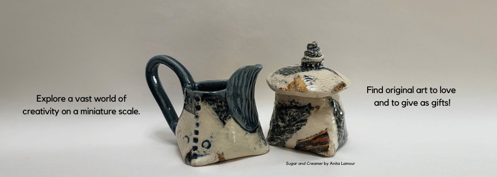 Two small ceramic teapot-style vessels with dark and cream glazing on a light background.