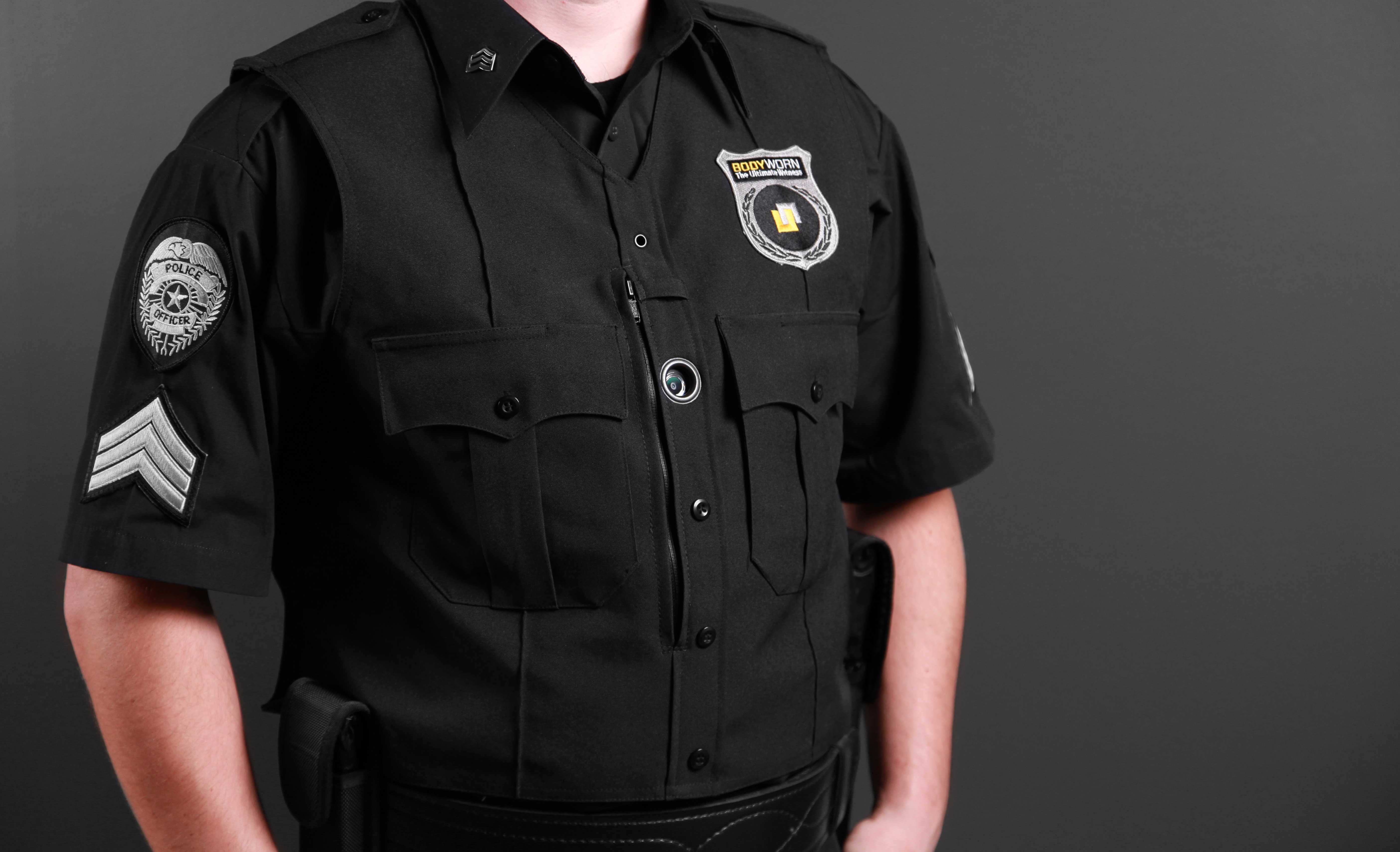 Police officer in black uniform with a body-worn camera clipped to the chest.