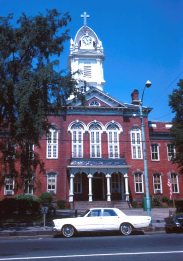 Historic red-brick courthouse with white clock tower and columned entrance portico.