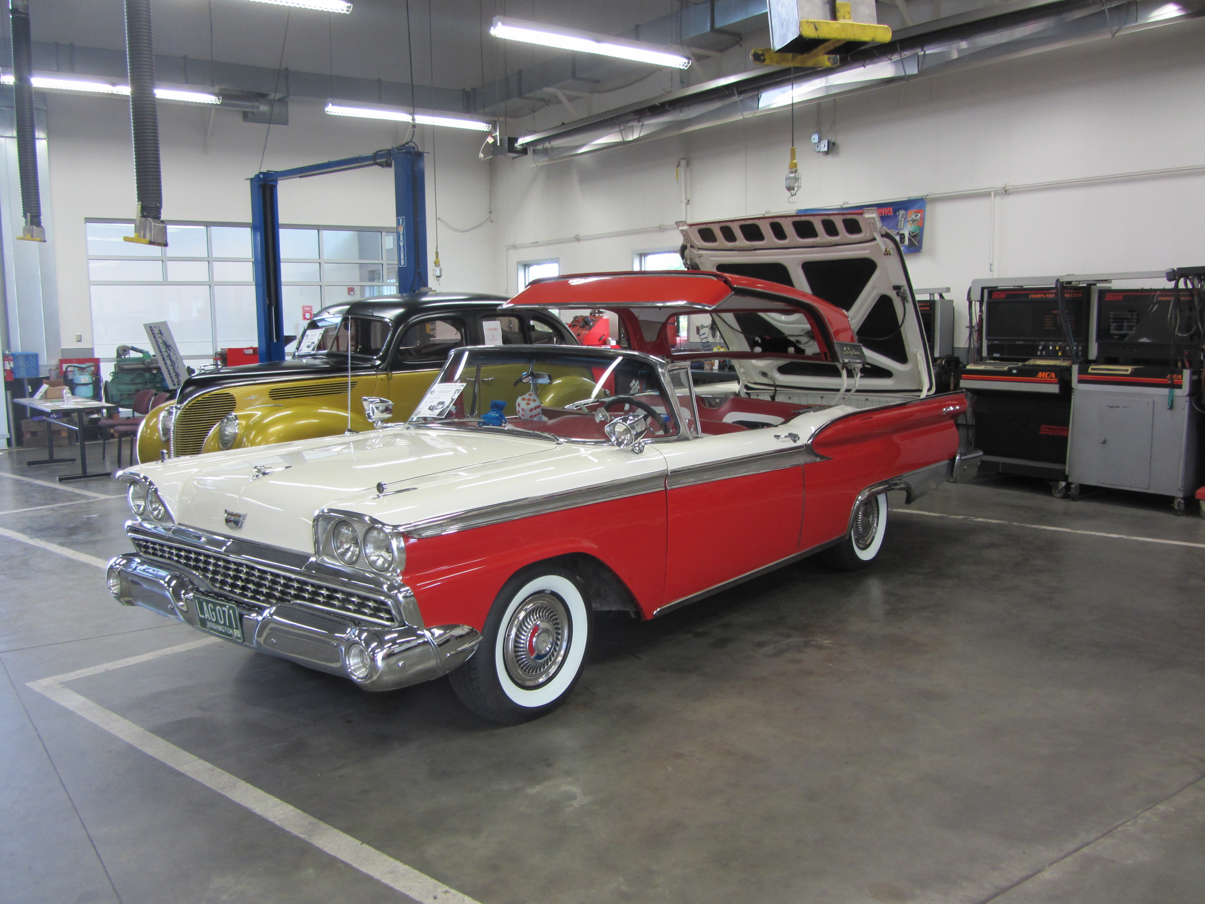 Classic cars displayed inside an automotive shop at a technical college facility.