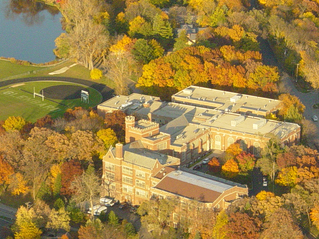Aerial view of a large brick high school campus surrounded by autumn-colored trees.