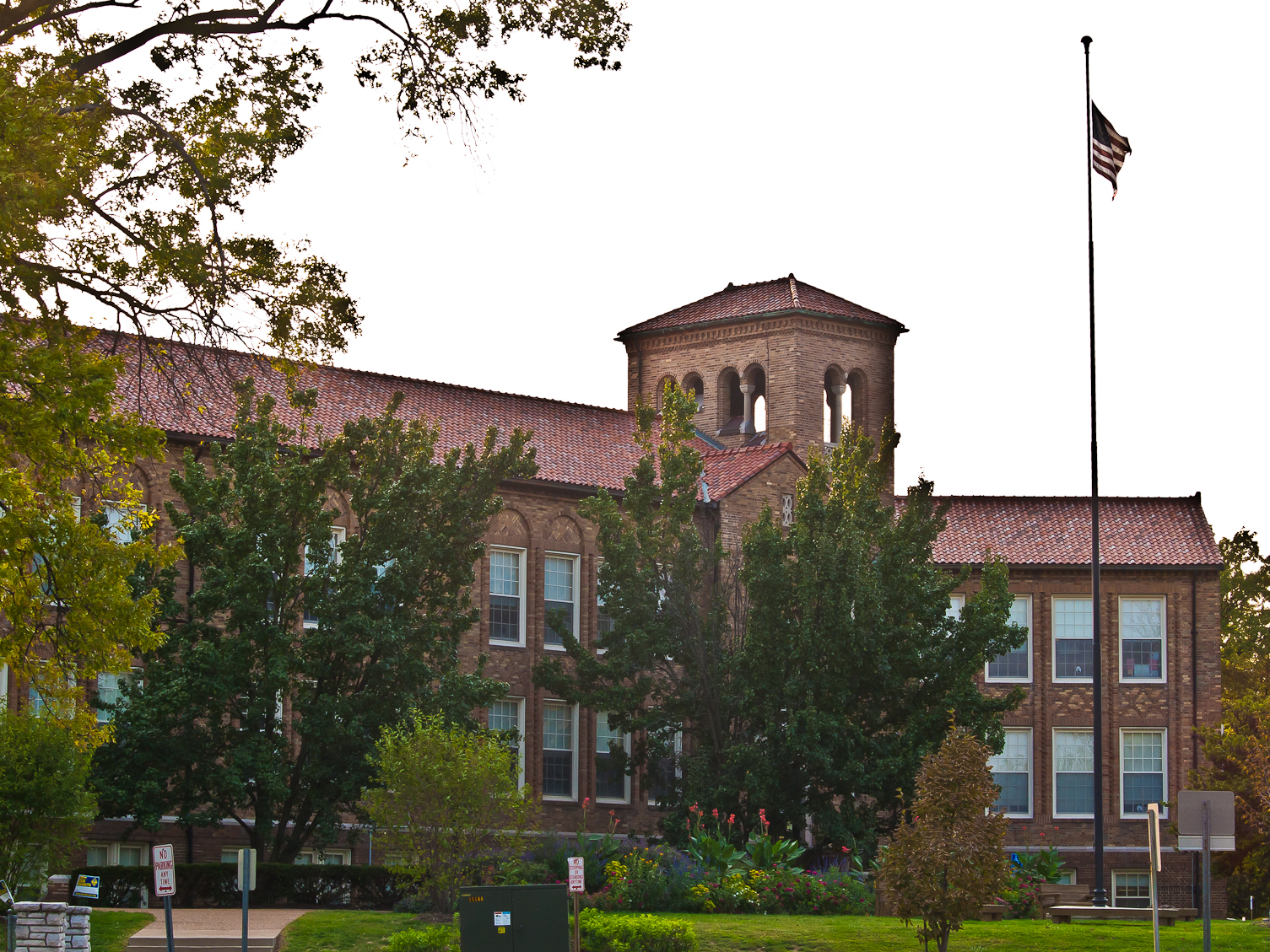 Brick school building with bell tower and American flag on a tall flagpole.