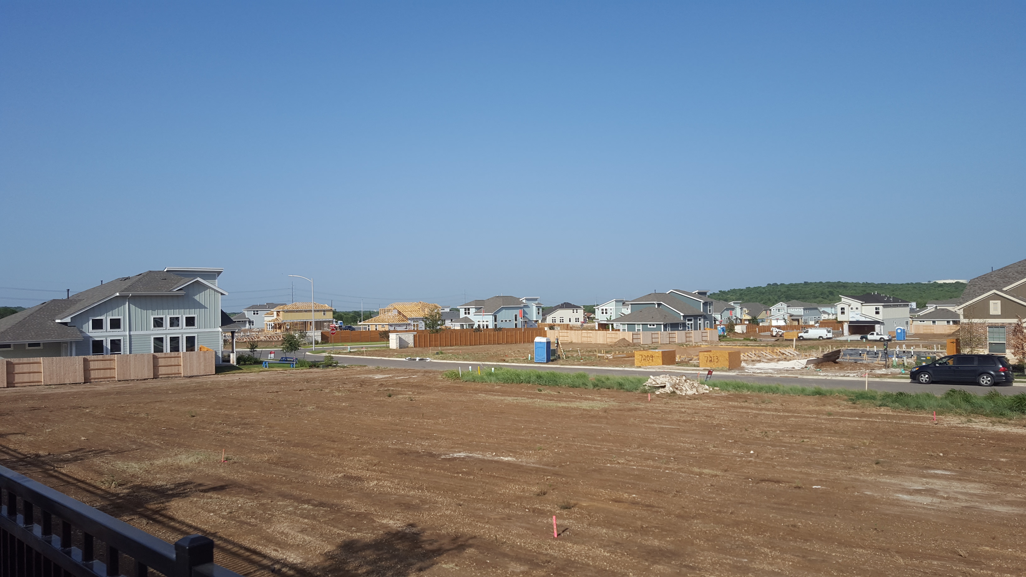 Framed new homes under construction on graded lots in a suburban subdivision.