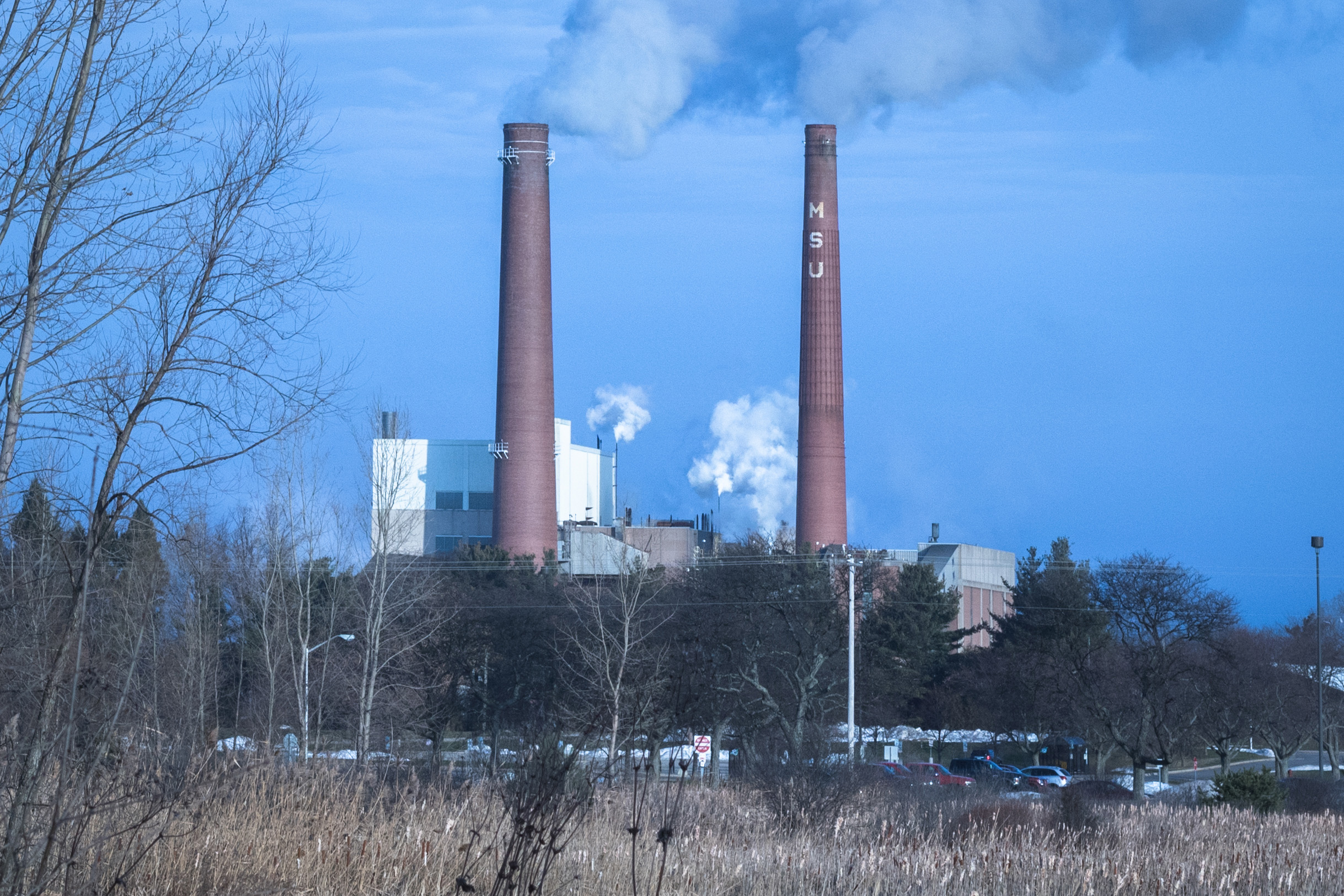 Two brick smokestacks labeled MSU emitting steam at a campus power plant.