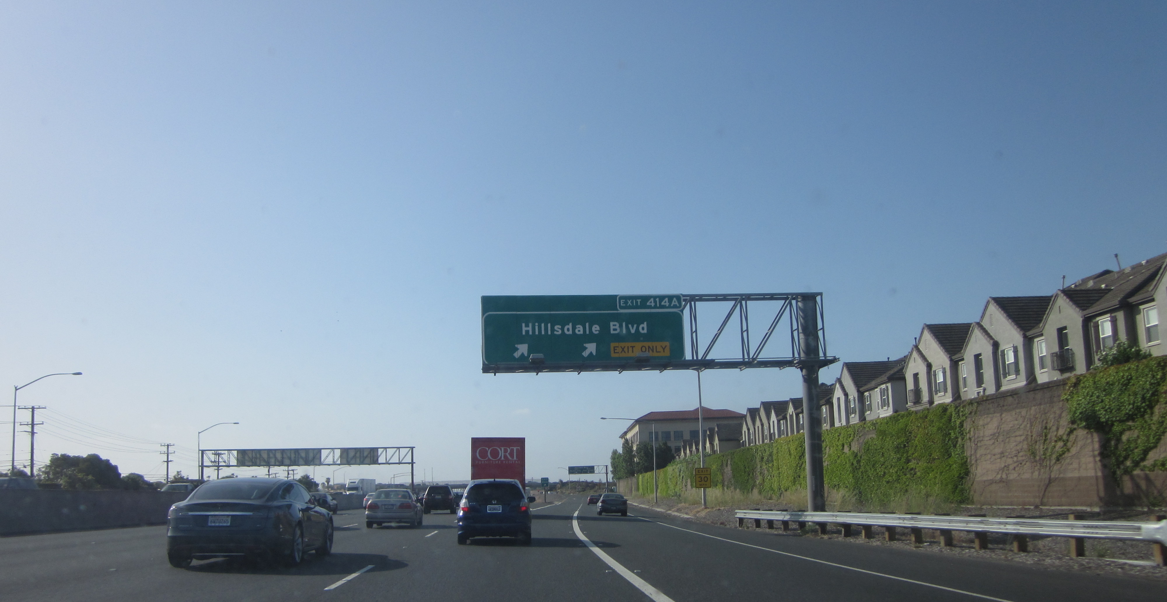 Multi-lane freeway with overpass and highway signs at Hillsdale Boulevard.