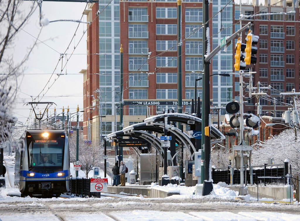 A light-rail train arrives at a snow-dusted station platform in Charlotte.