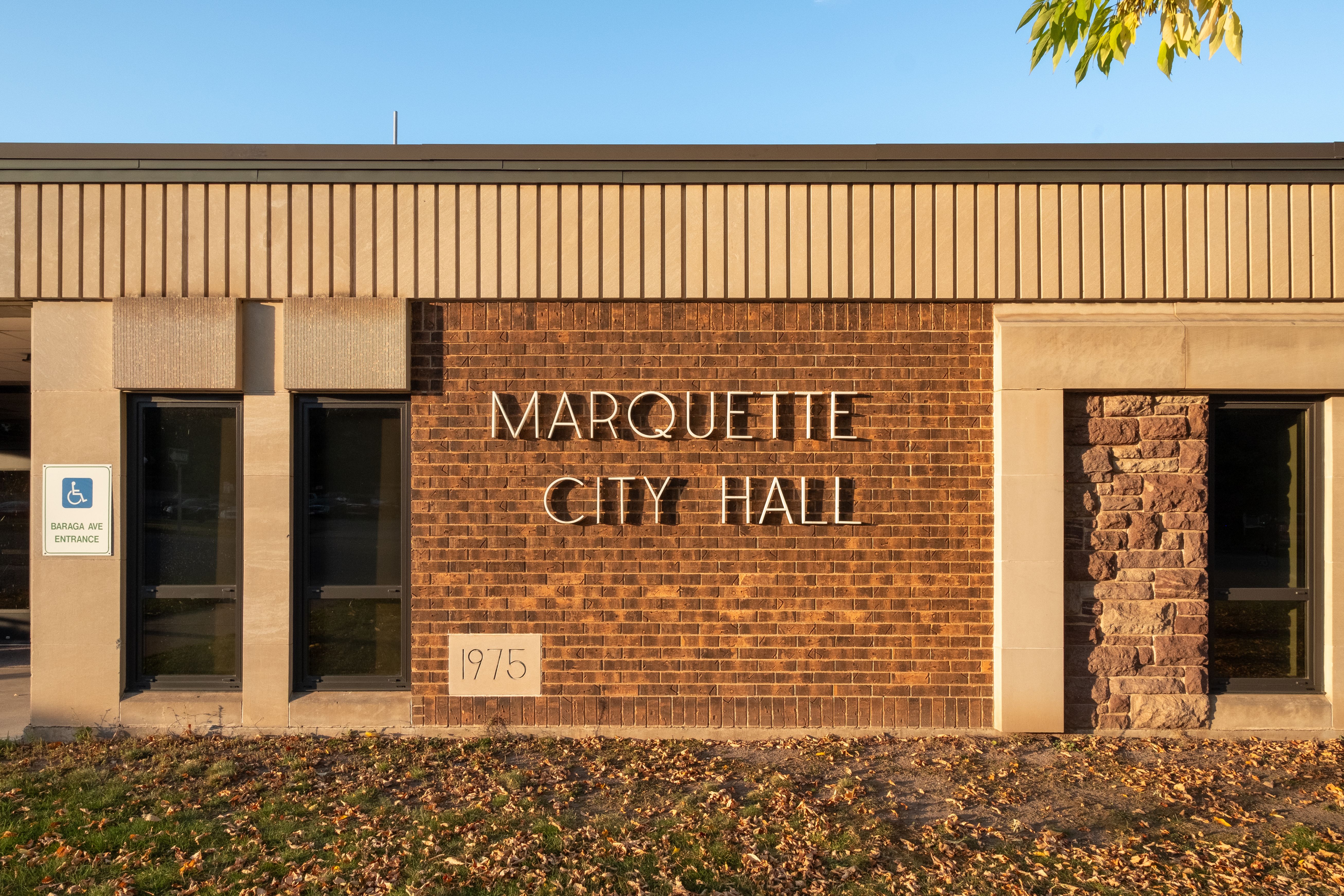 Brick exterior of Marquette City Hall with metal lettering and a 1975 datestone.