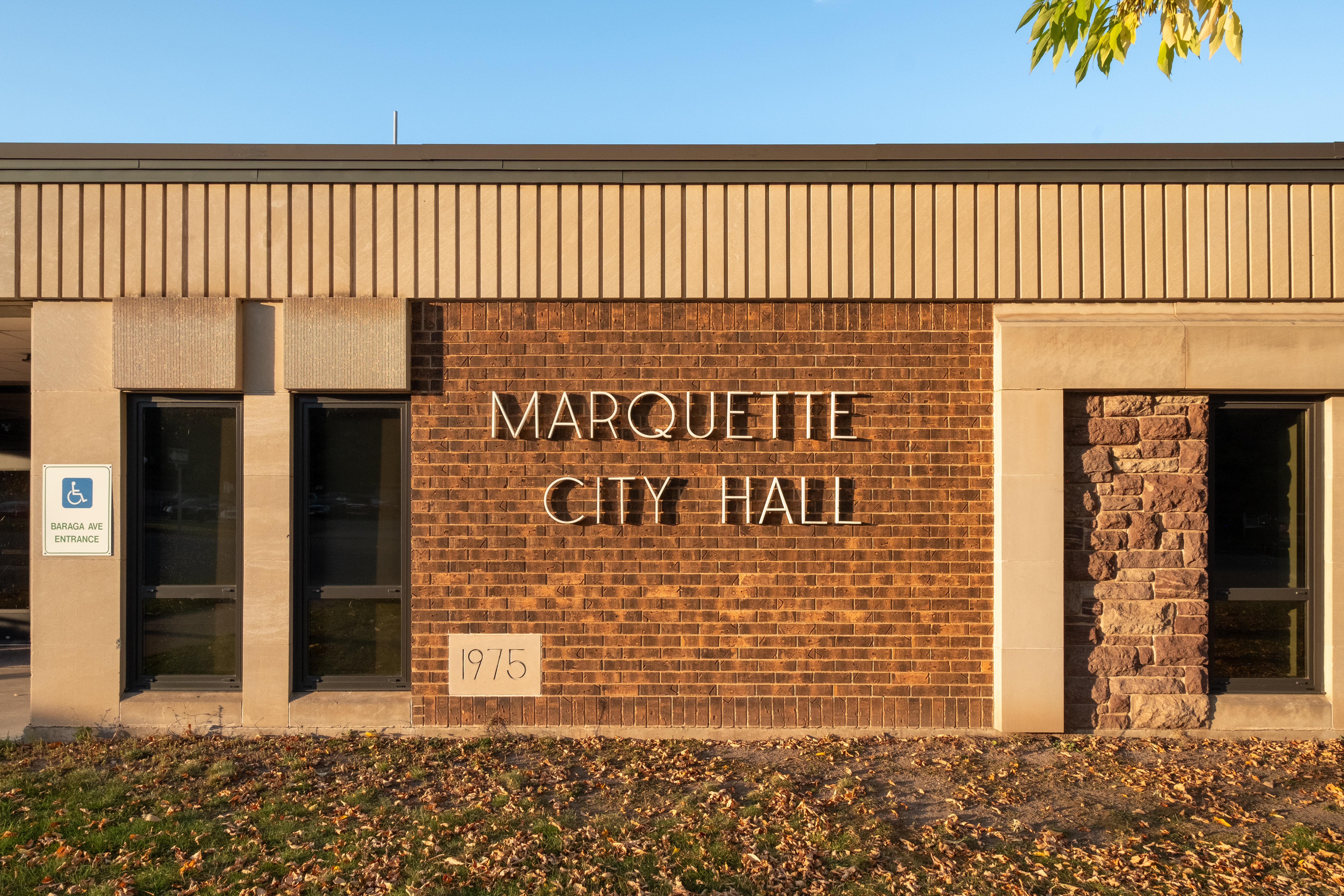 Brick exterior of a municipal building with metal letters reading Marquette City Hall.
