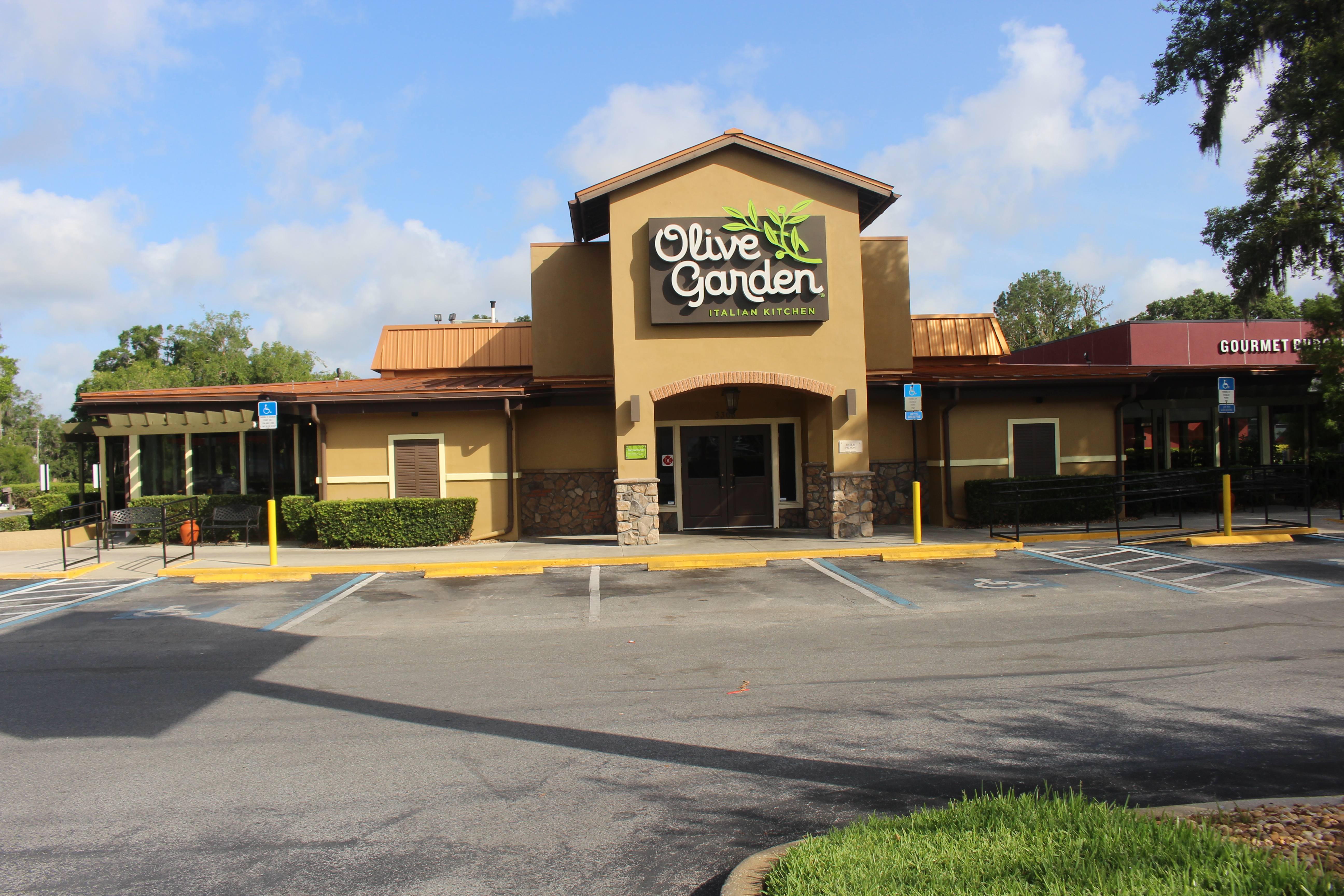Olive Garden restaurant exterior with tan stucco walls, signage, and a parking lot.