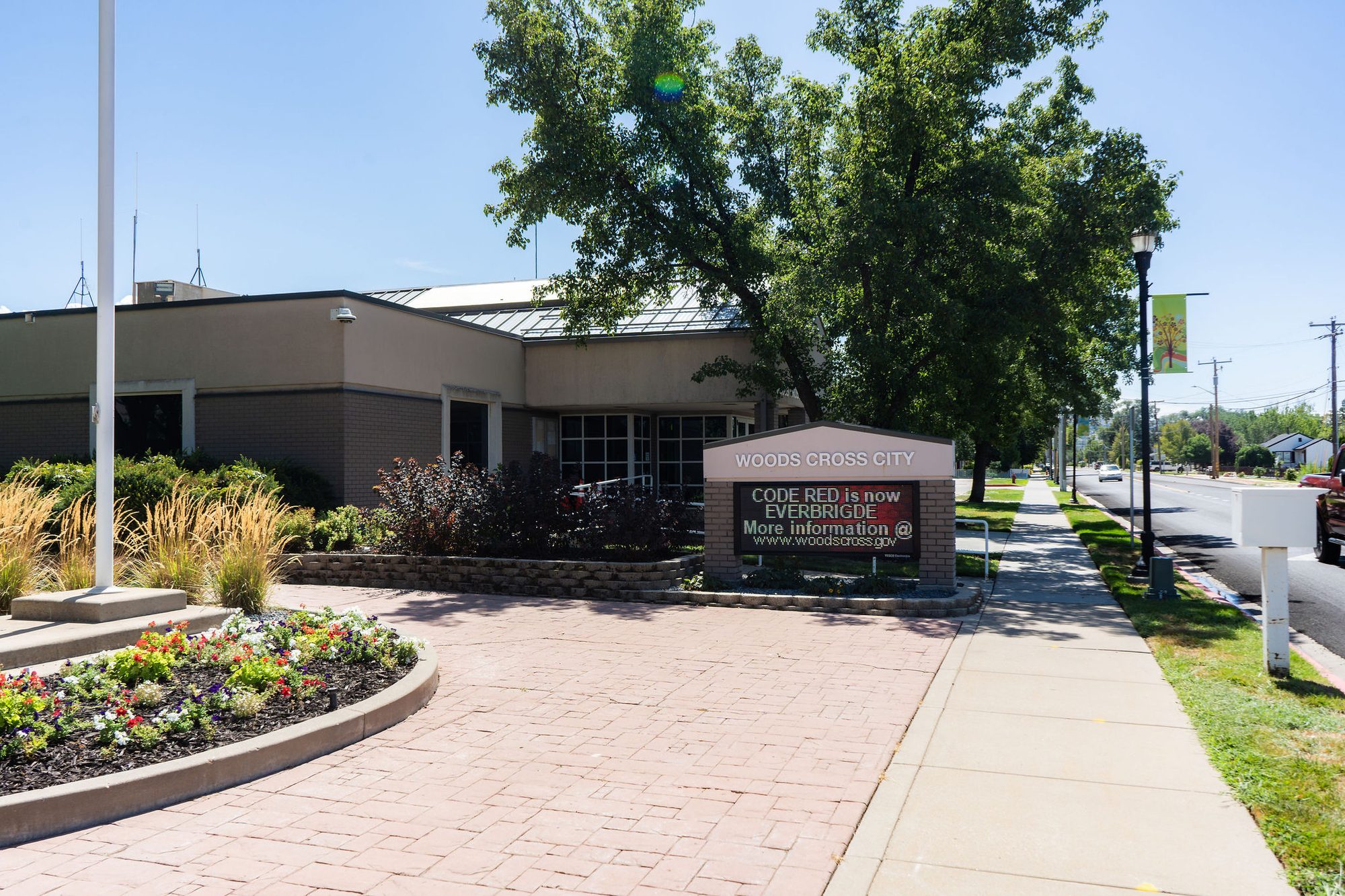 Low single-story city hall building with brick plaza and marquee sign.