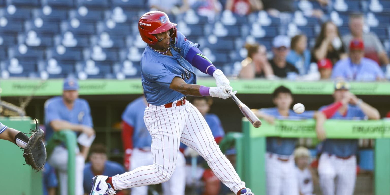 Baseball batter in light blue pinstripe uniform and red helmet makes contact with a pitch.
