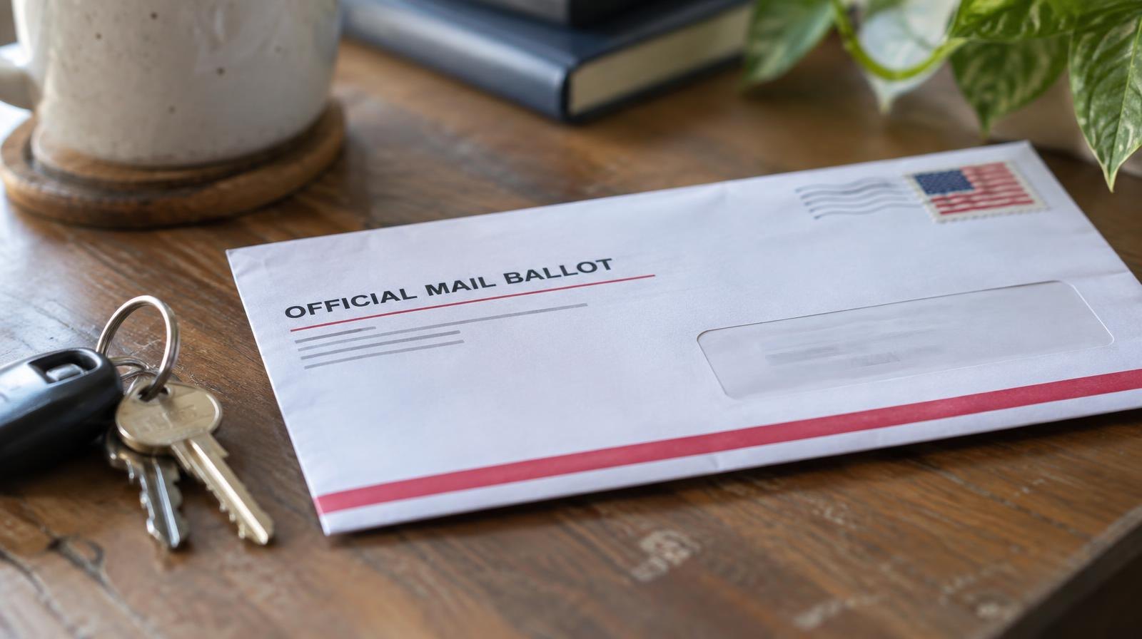 A sealed mail ballot return envelope resting on a wooden surface.