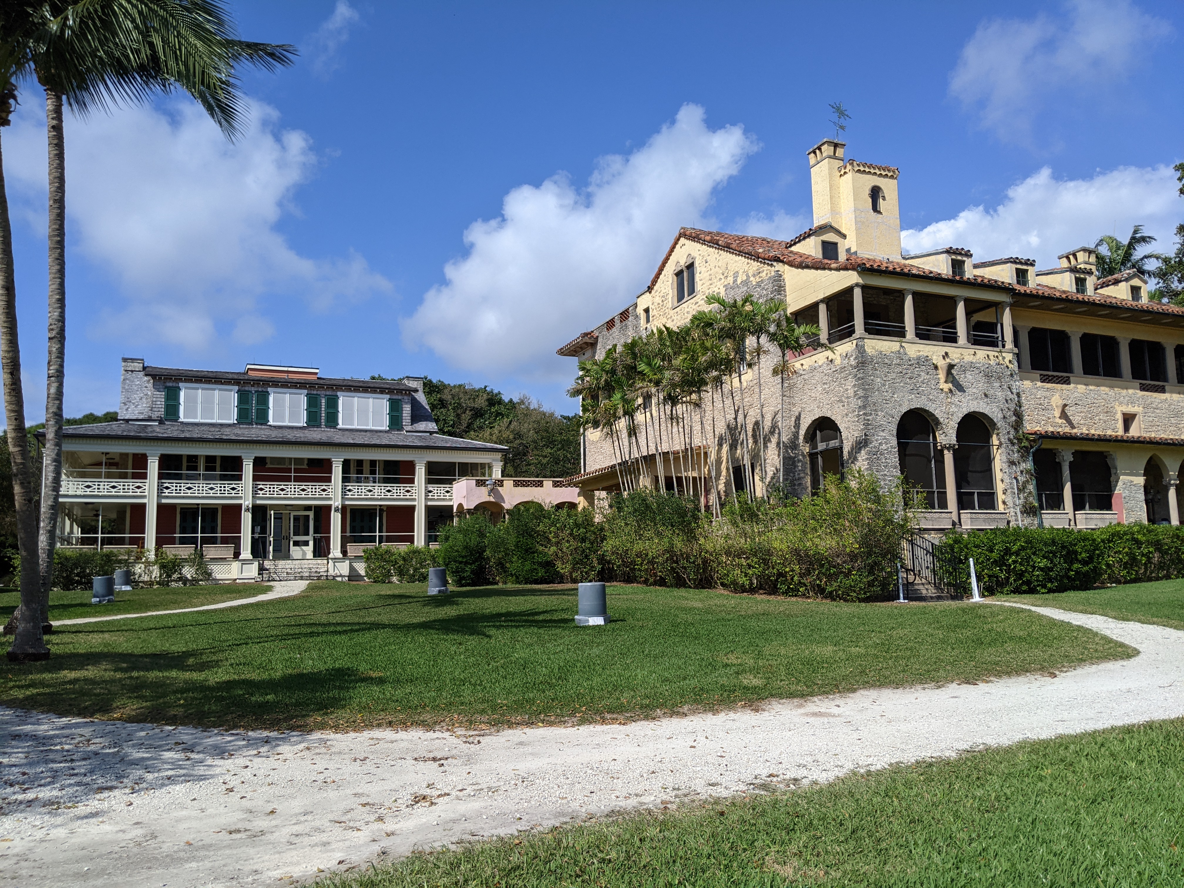 Two historic buildings at the Deering Estate surrounded by palm trees and tropical landscaping.