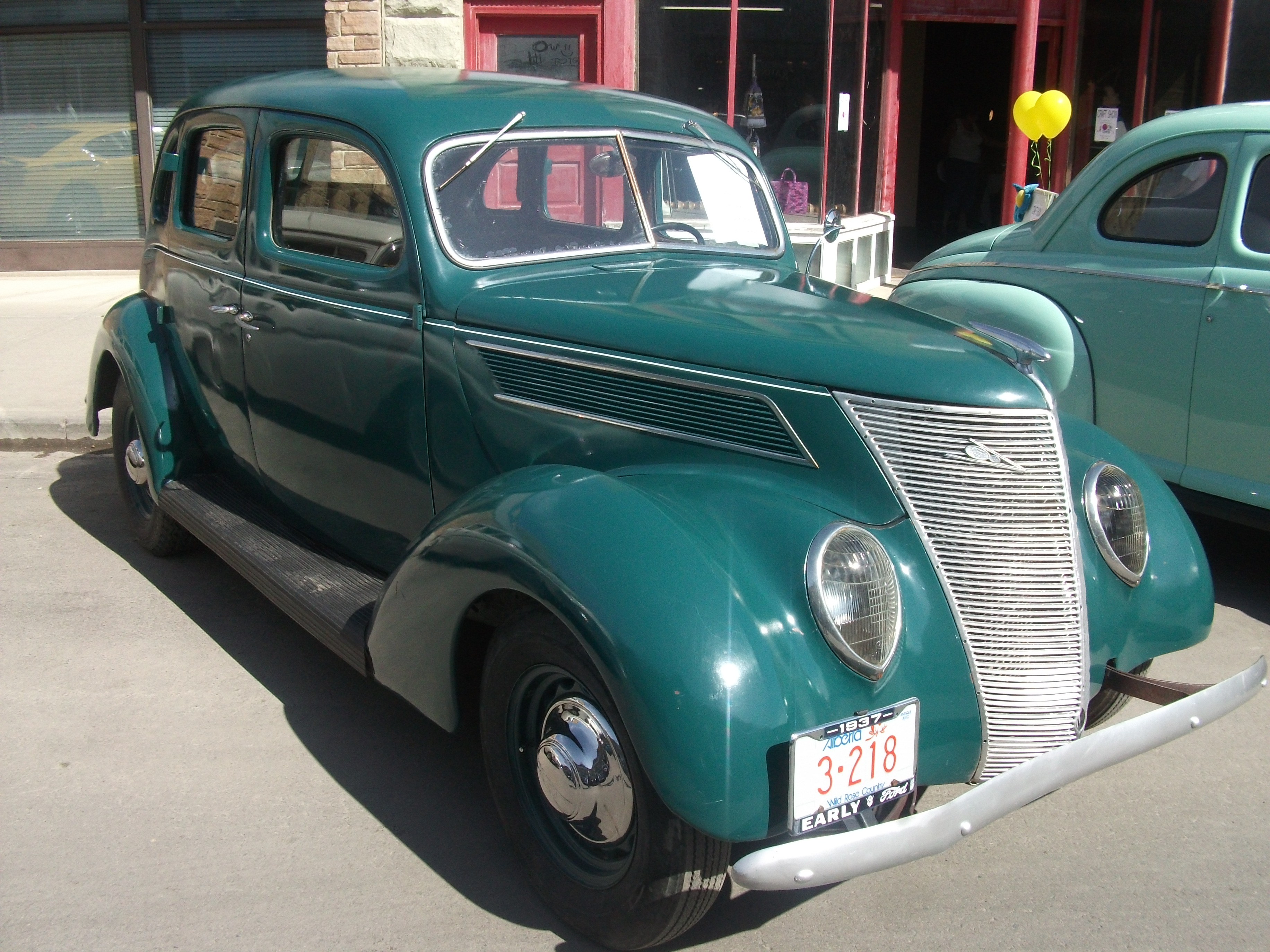 Teal 1937 Ford Slantback sedan parked at an outdoor classic car show.