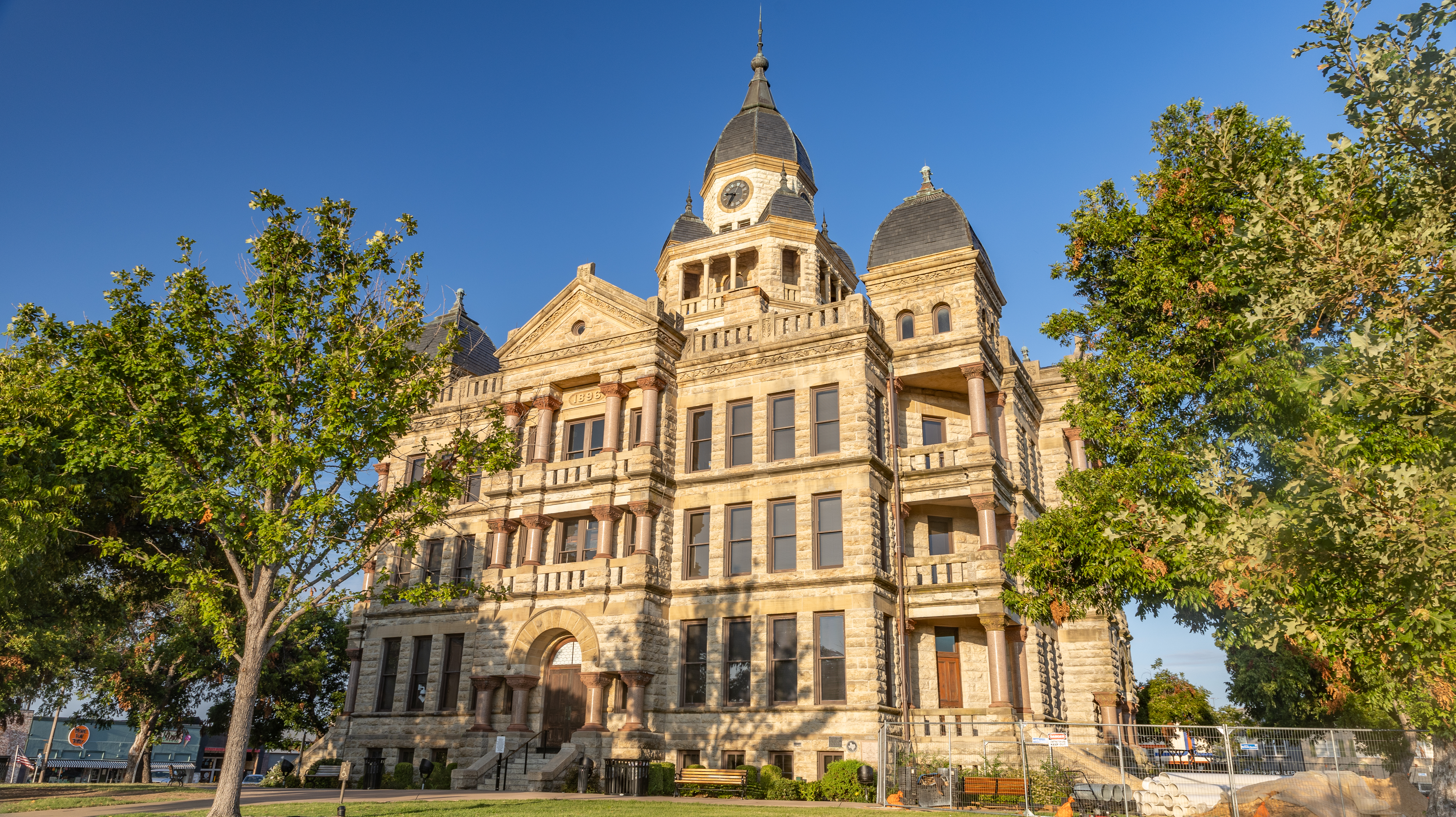 Historic stone courthouse with a central clock tower and corner turrets under blue sky.