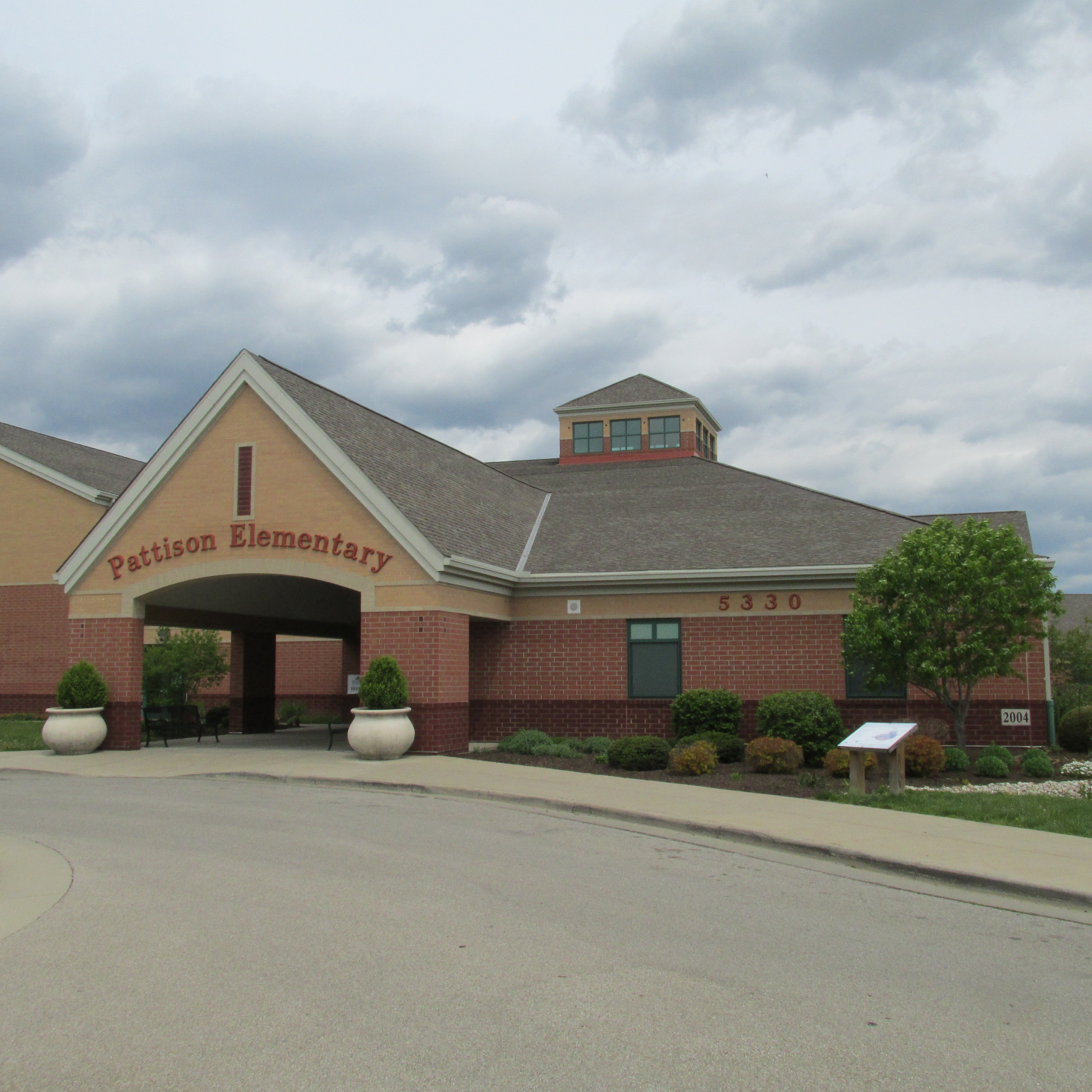 Single-story brick elementary school with covered entrance and address number visible on facade.