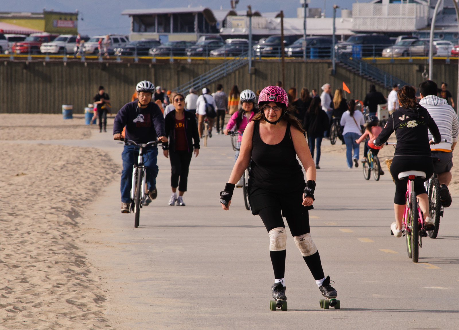 Cyclists and pedestrians share a paved beachside path alongside a sandy beach.