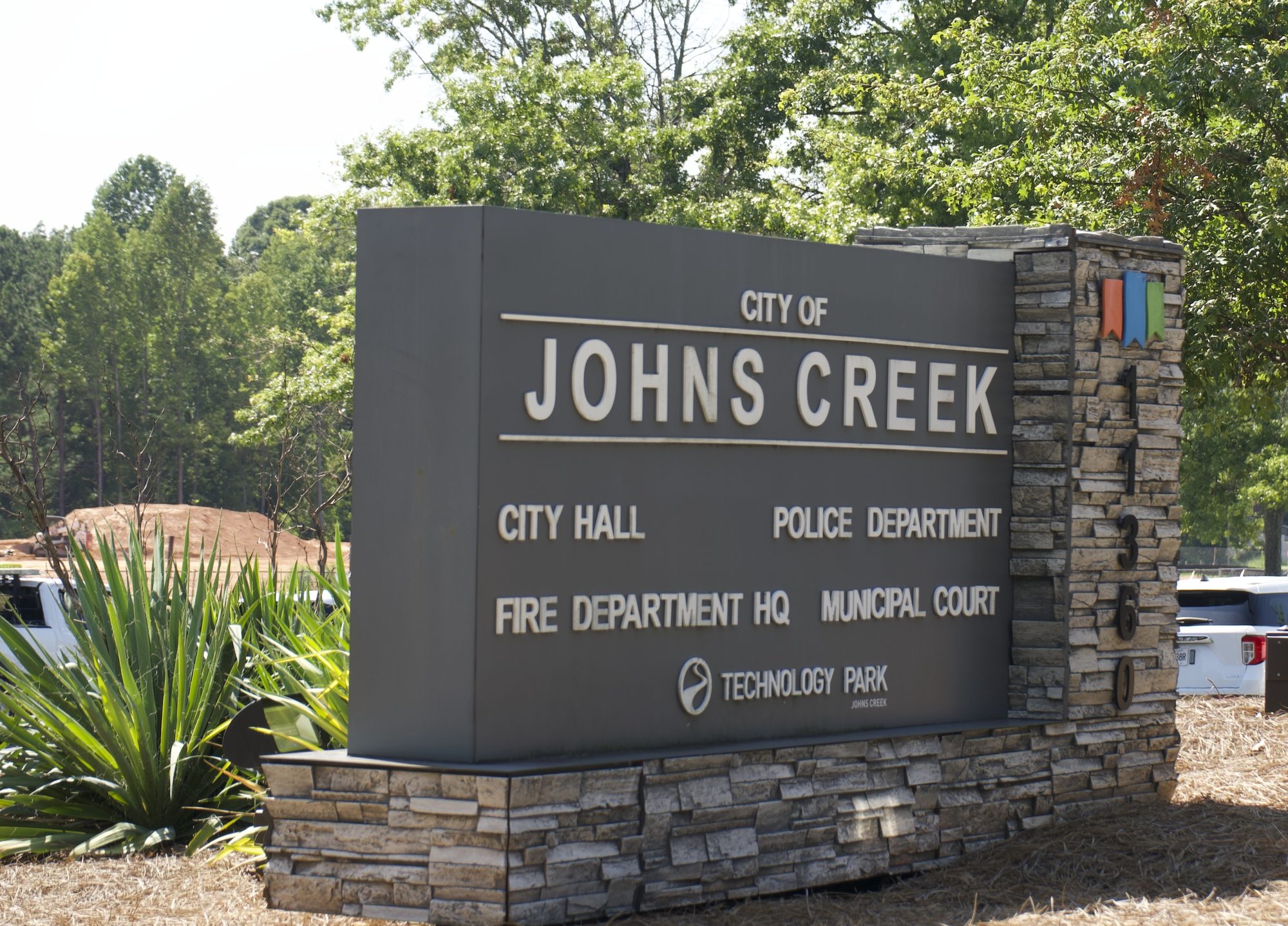 Stone and metal monument sign listing Johns Creek city government offices and departments.