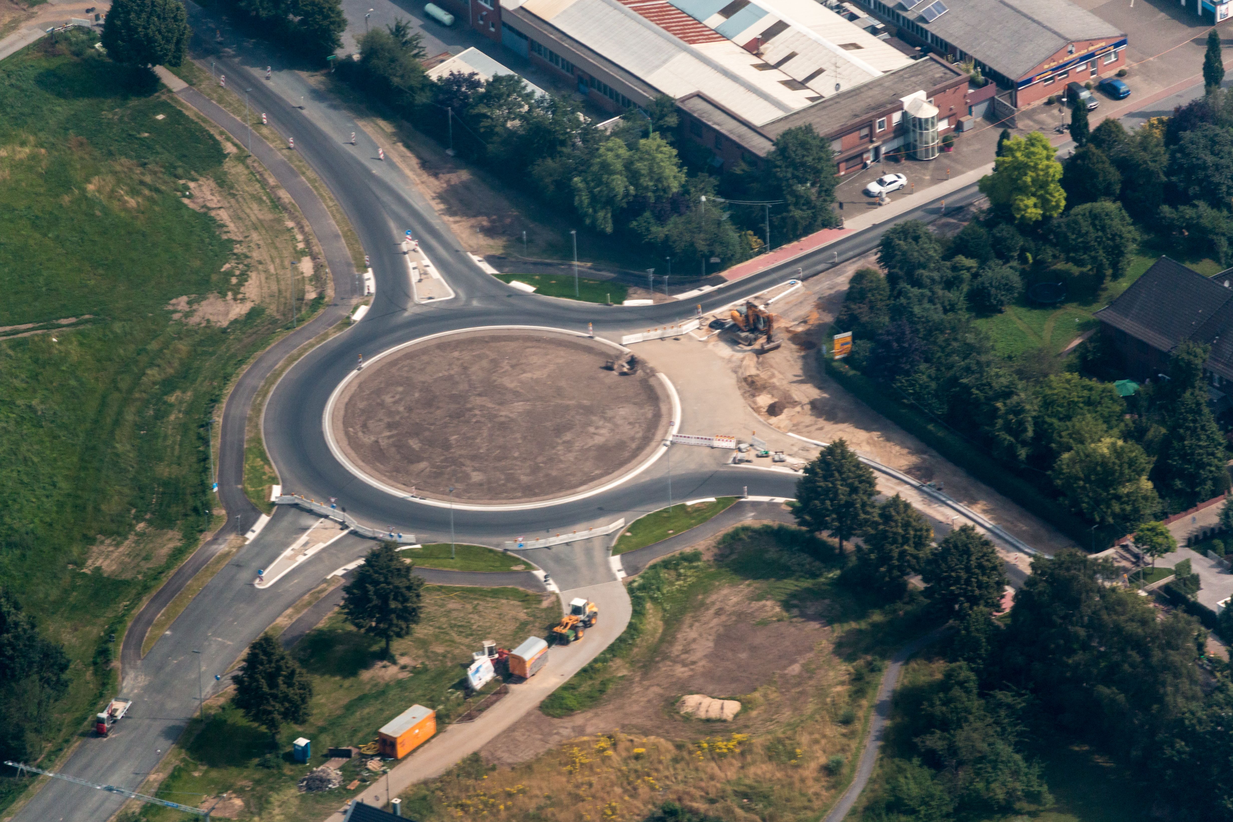 Aerial view of a large circular roundabout with a dirt center island and multiple approach roads.